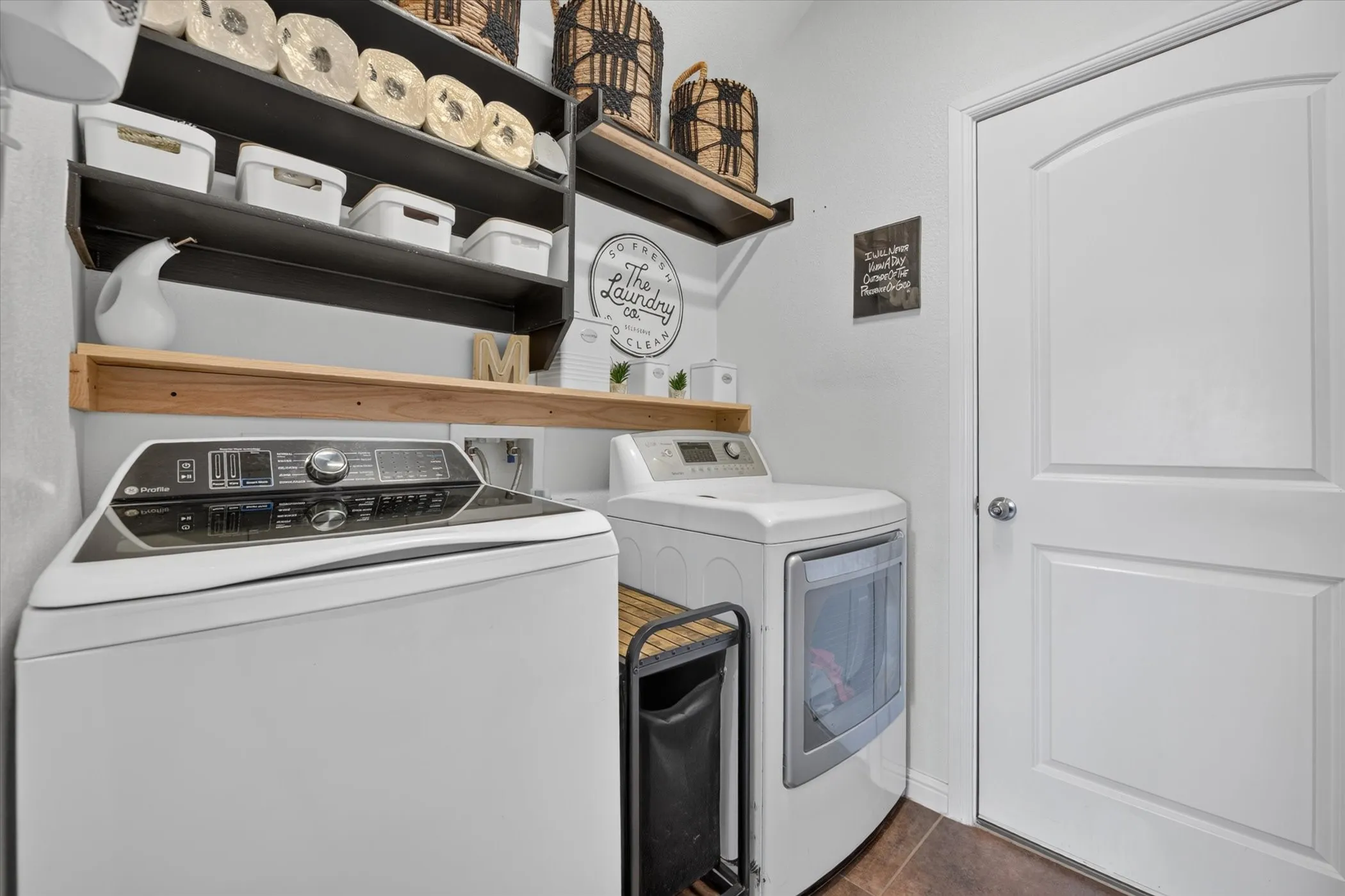 Dedicated utility space featuring a washer and dryer, built-in shelving, and wood-finish flooring