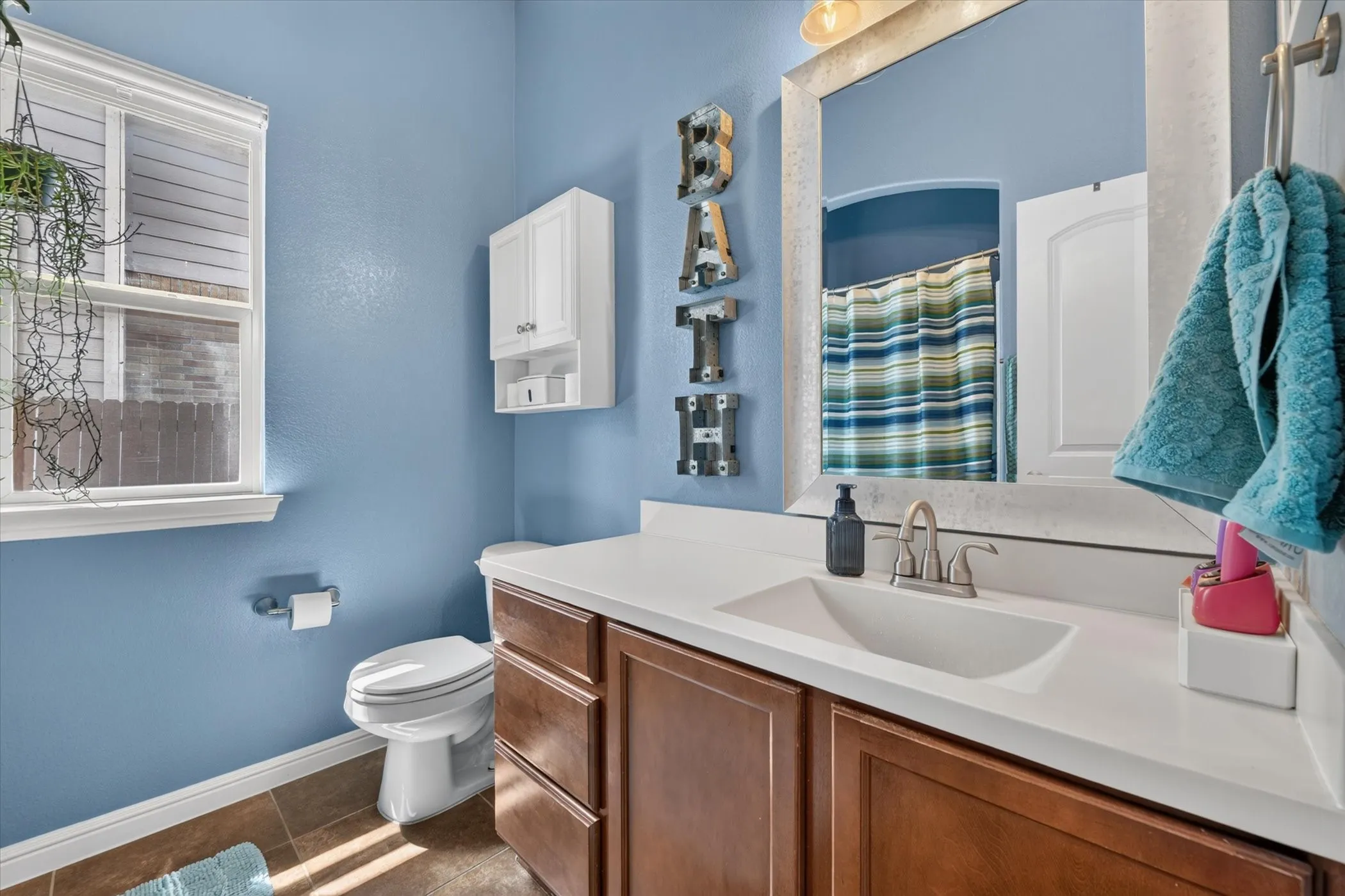 Built-in vanity with a single basin sink, white countertop, and wood-finish cabinetry