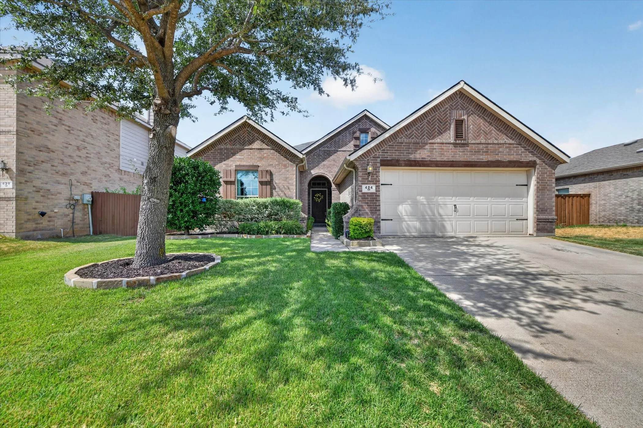 Brick exterior with an arched entryway, attached garage, and a concrete driveway