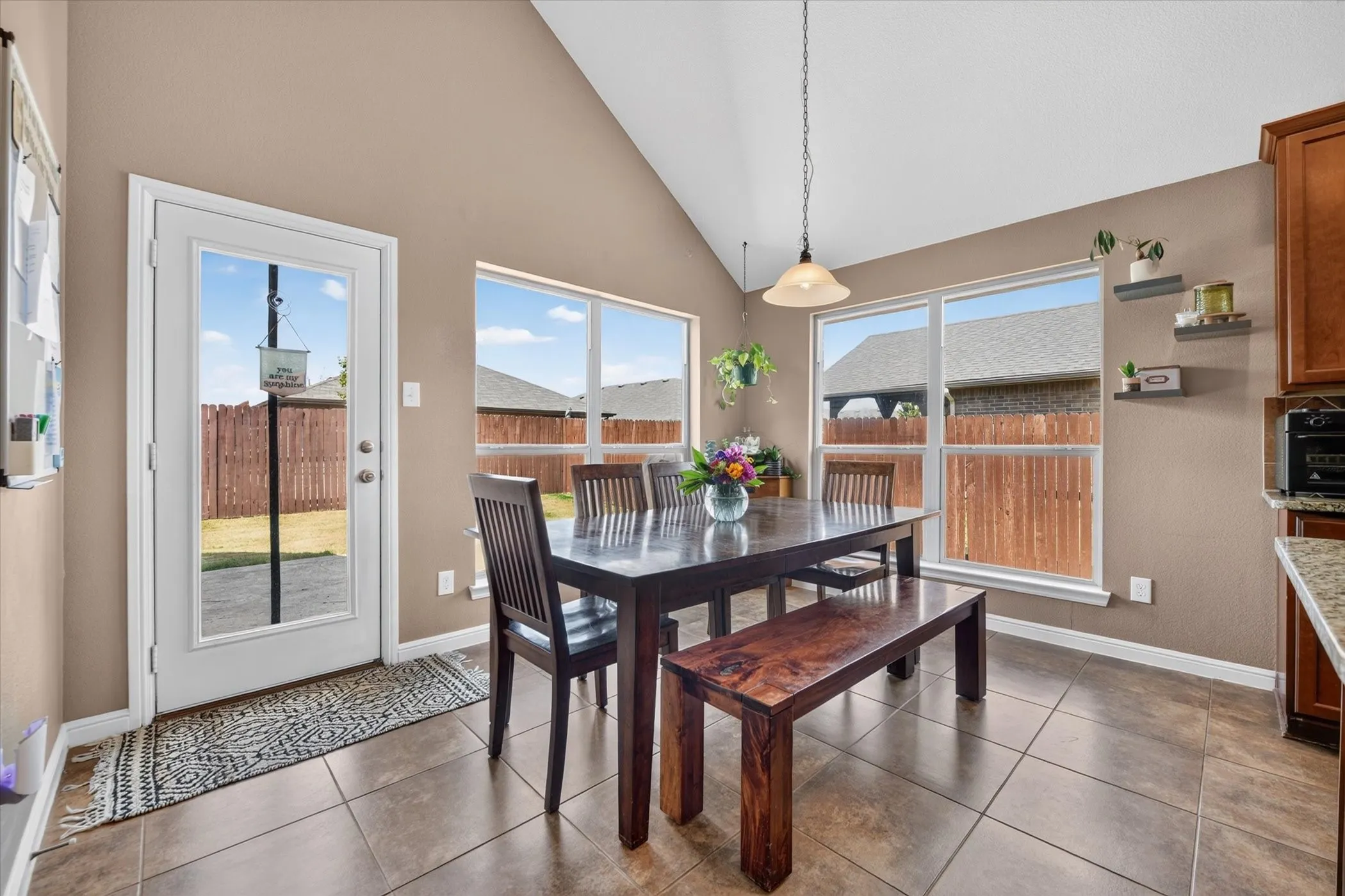 Vaulted ceiling, tiled flooring, built-in shelving, white trim, and a glass-paneled exterior door