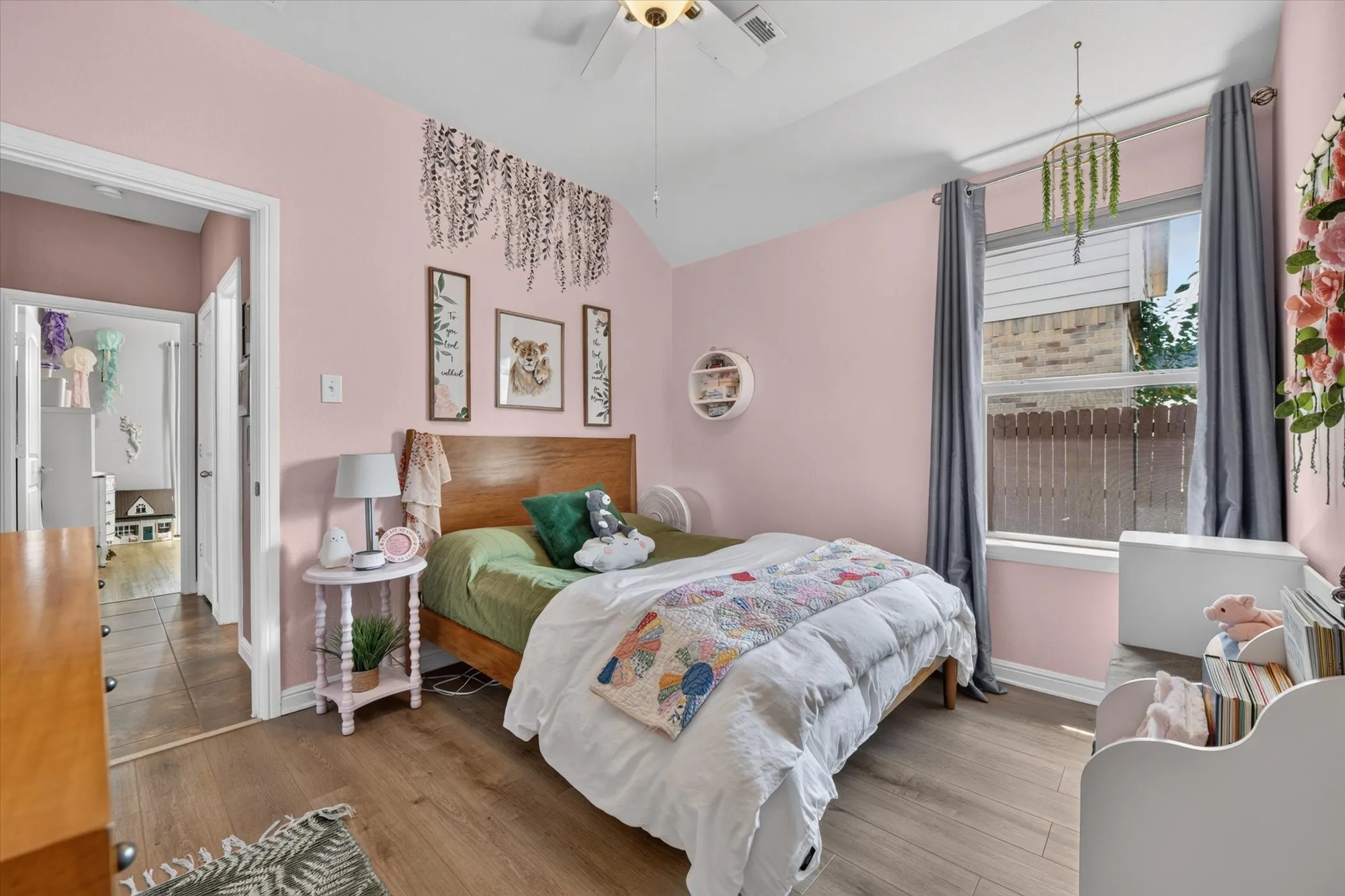 Vaulted ceiling with a ceiling fan, wood-finish flooring, and a window with drapery