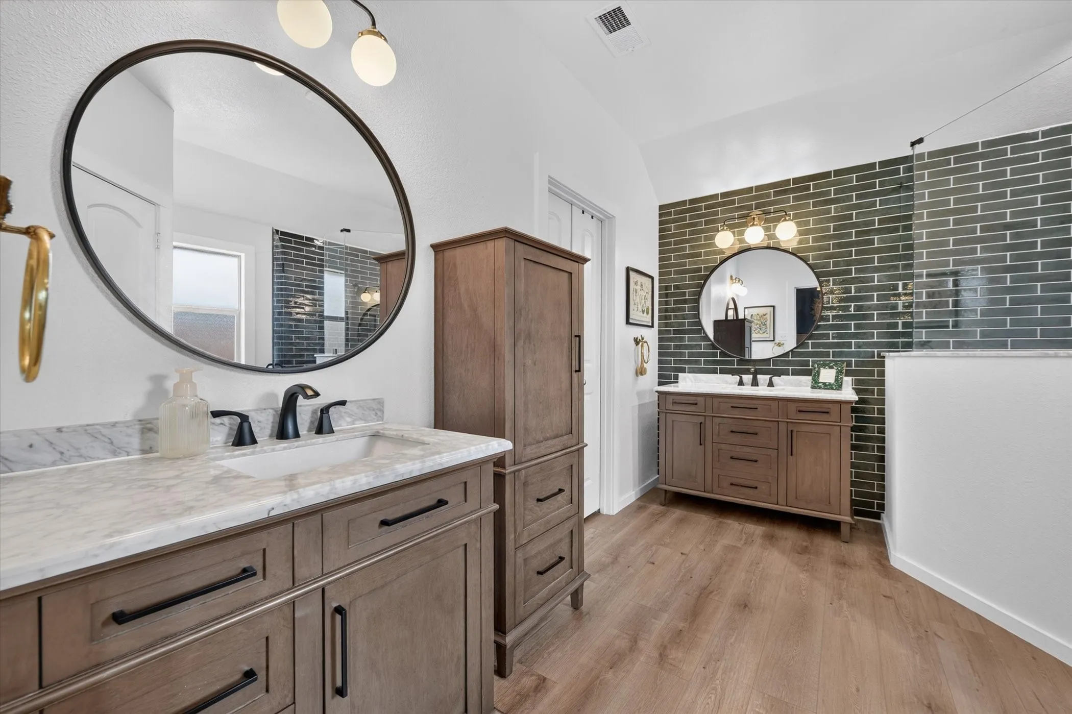 Dual wood-finish vanities with undermount sinks and dark hardware