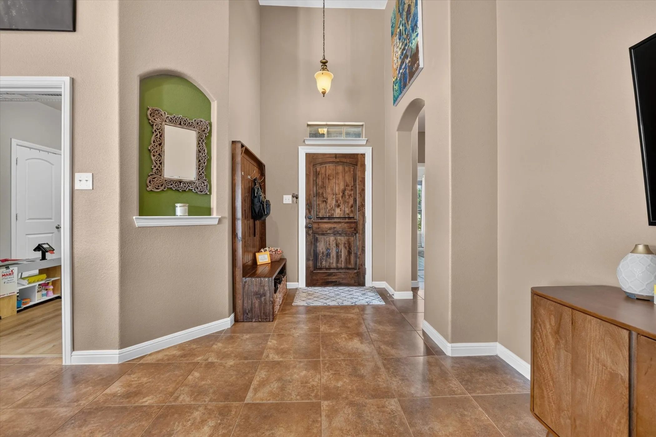 Tiled flooring, arched doorway, recessed wall niche, natural wood-finish door, pendant light fixture