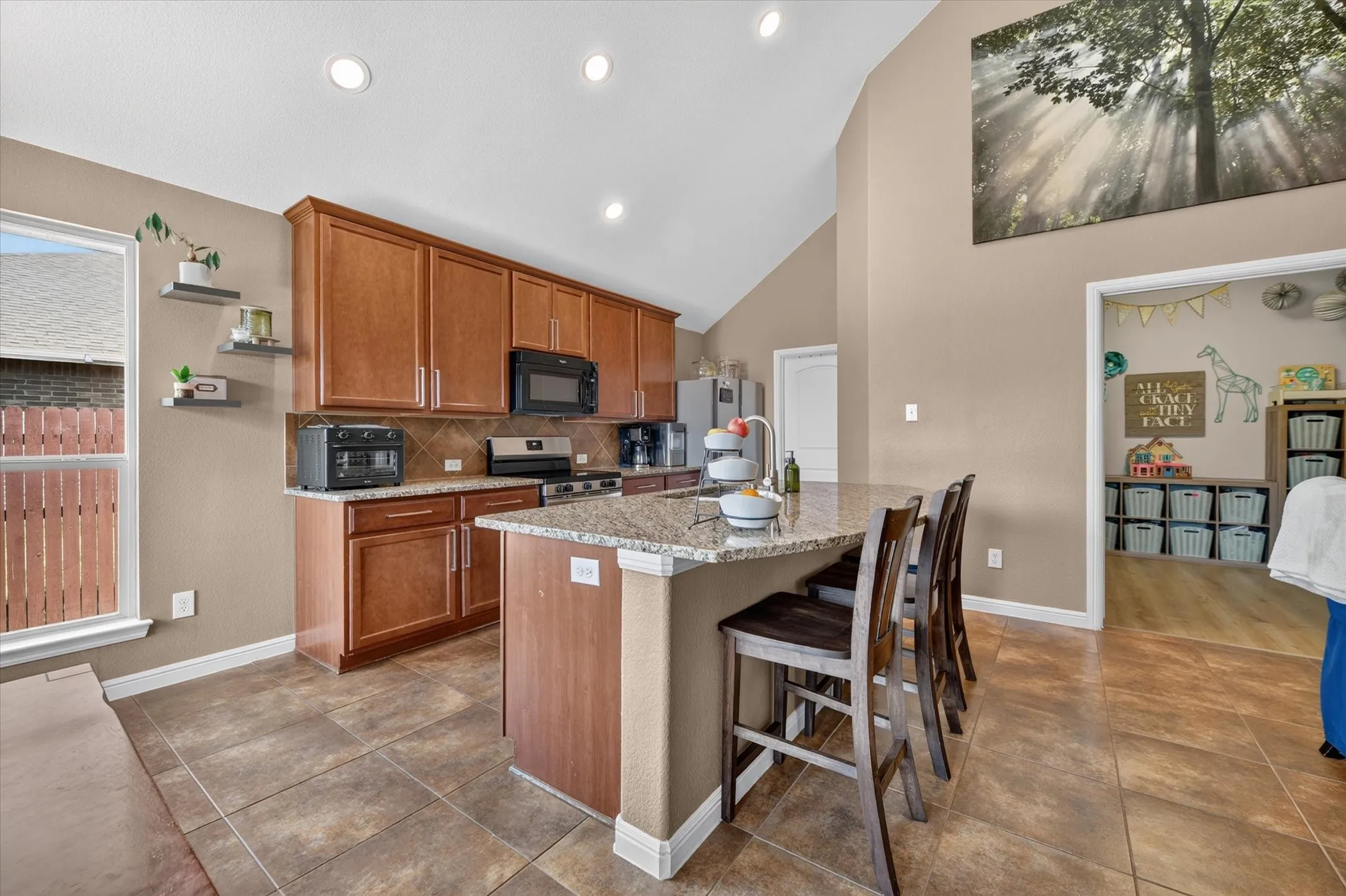 Kitchen featuring a vaulted ceiling, recessed lighting, wood cabinetry, stone countertops, and tile flooring