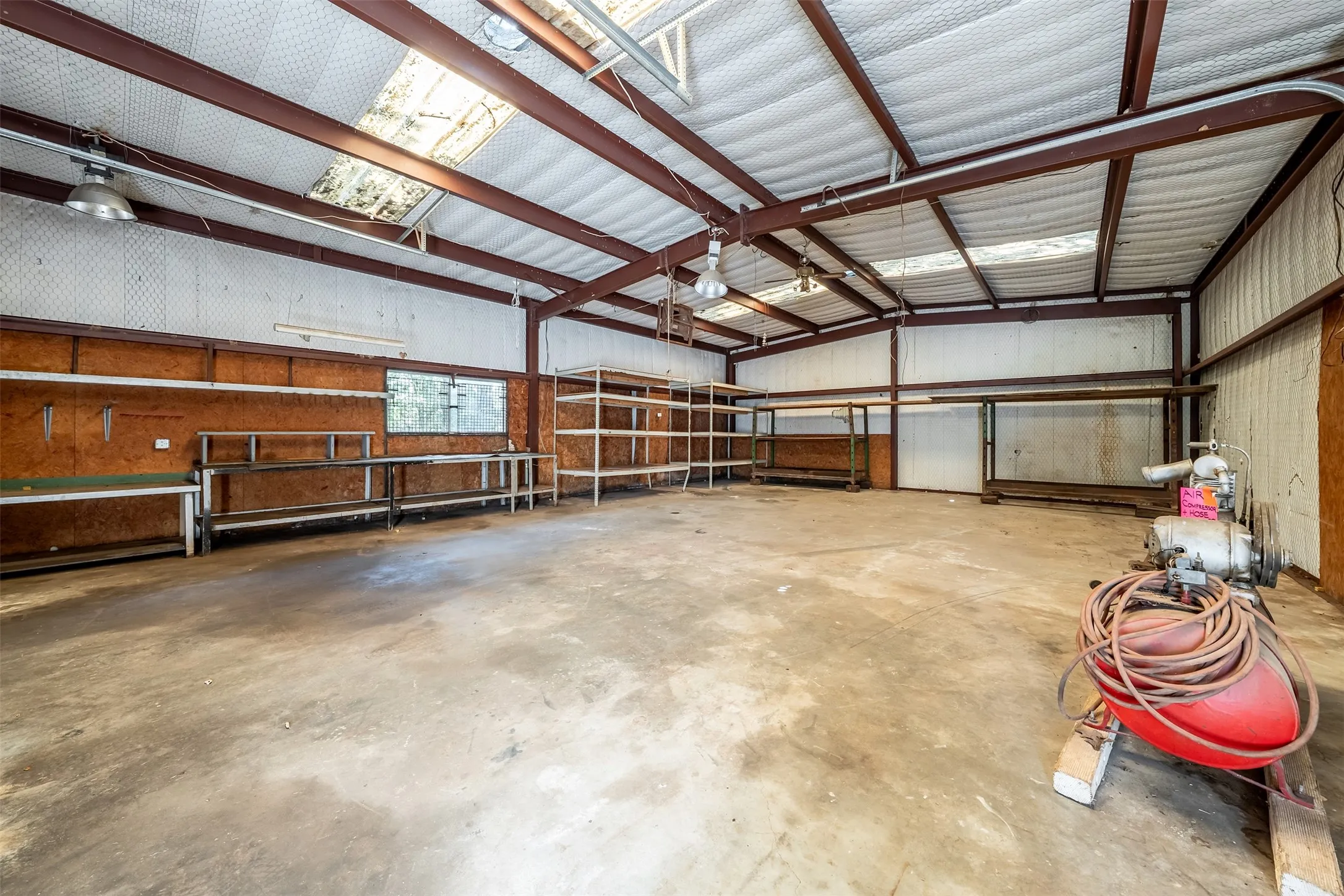 Spacious interior featuring a concrete floor, exposed structural beams, ceiling-mounted lighting, and integrated shelving units