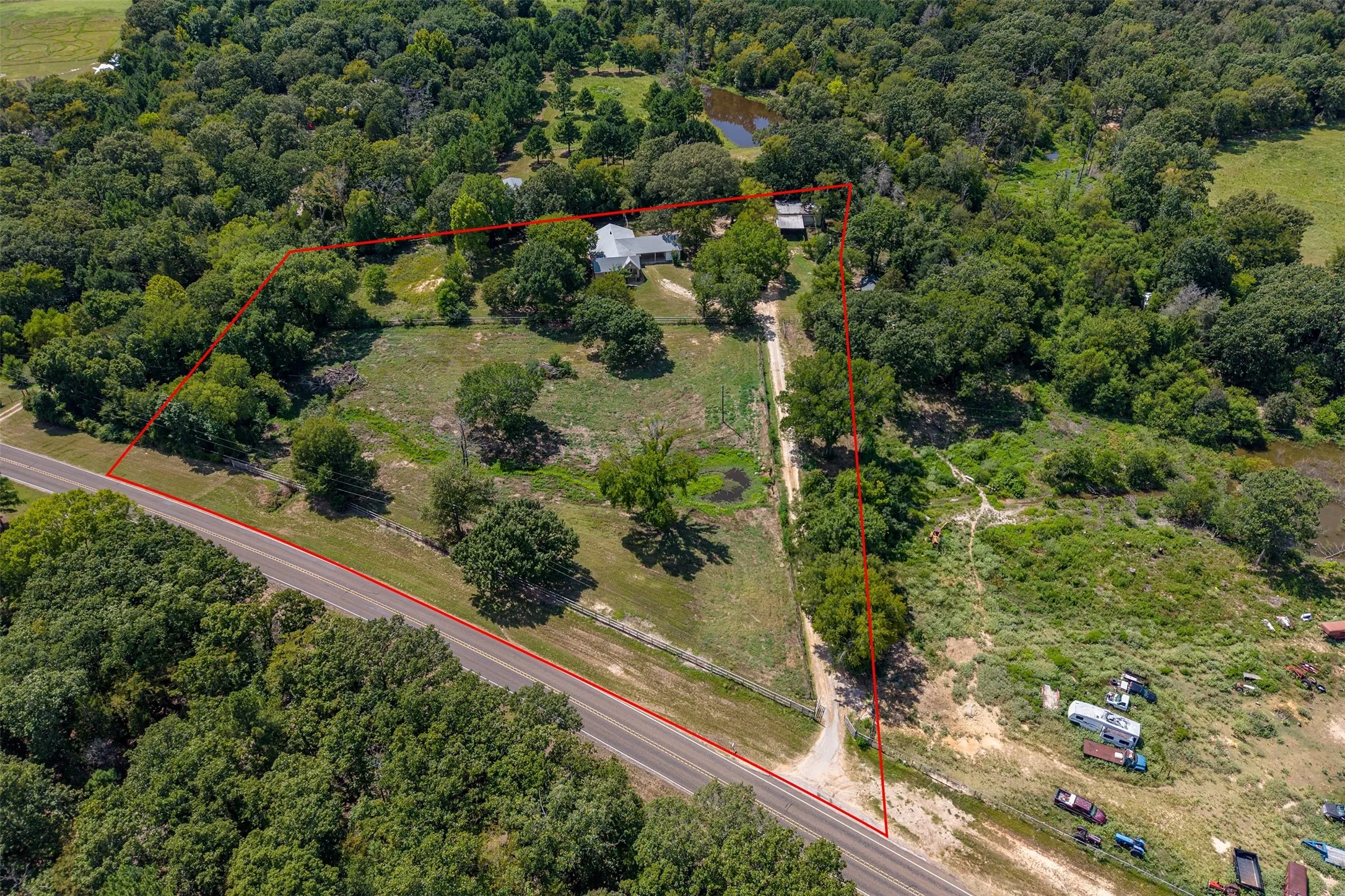 Expansive rural property featuring mature landscaping and established trees throughout the grounds