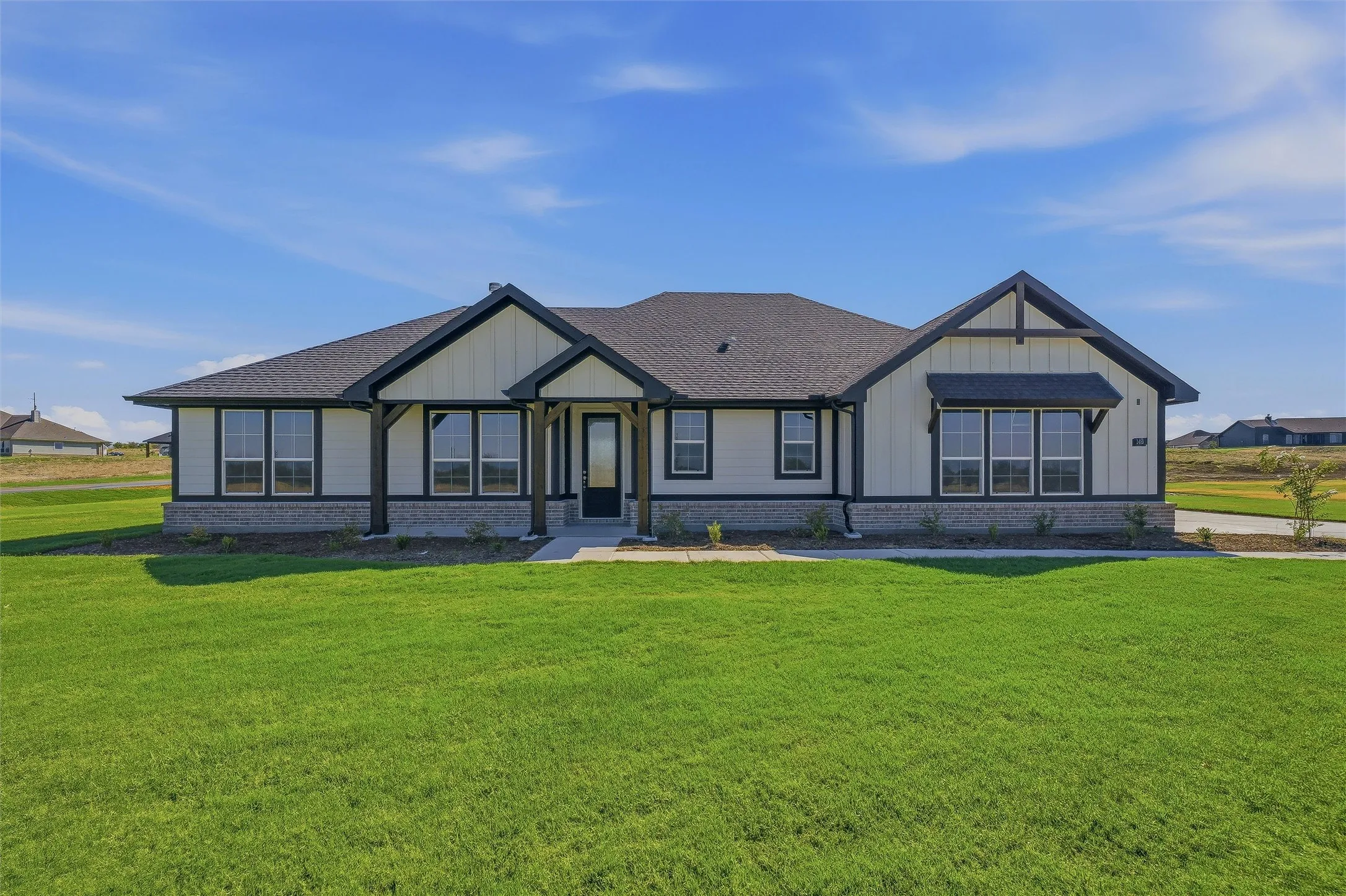 Modern farmhouse exterior featuring board and batten siding, dark trim, a covered entry, and multiple large windows