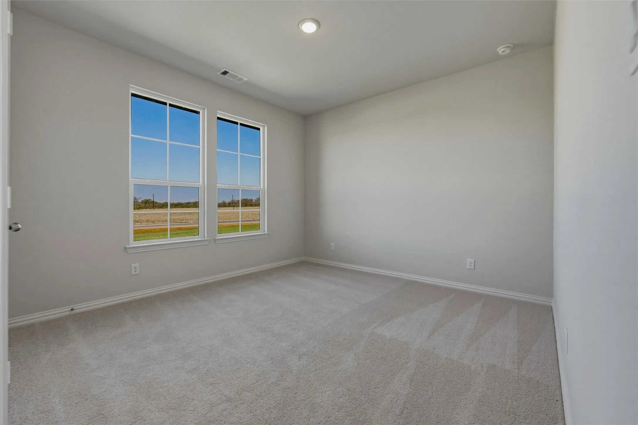 Soft gray wall paint with white trim, light gray carpet flooring, and two double-hung windows