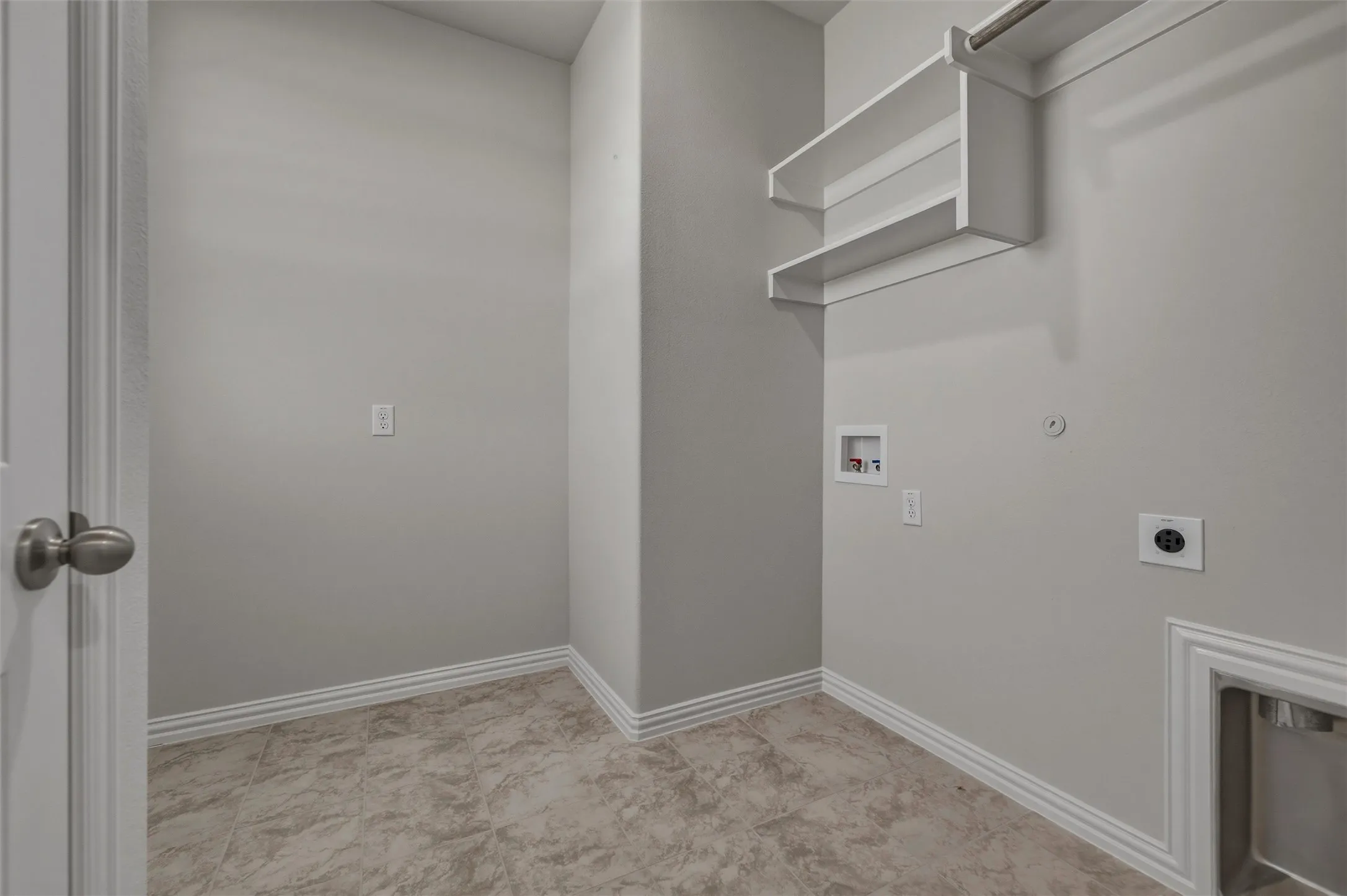 Laundry area featuring built-in shelving, a hanging rod, and tile flooring