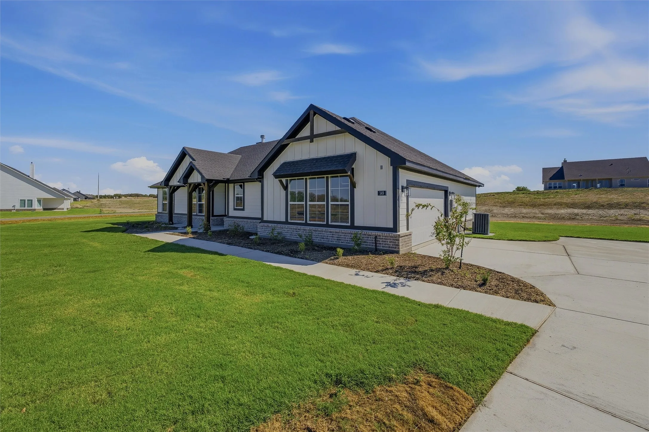 Exterior featuring board and batten siding, stone accents, dark trim, an attached garage, and a concrete driveway