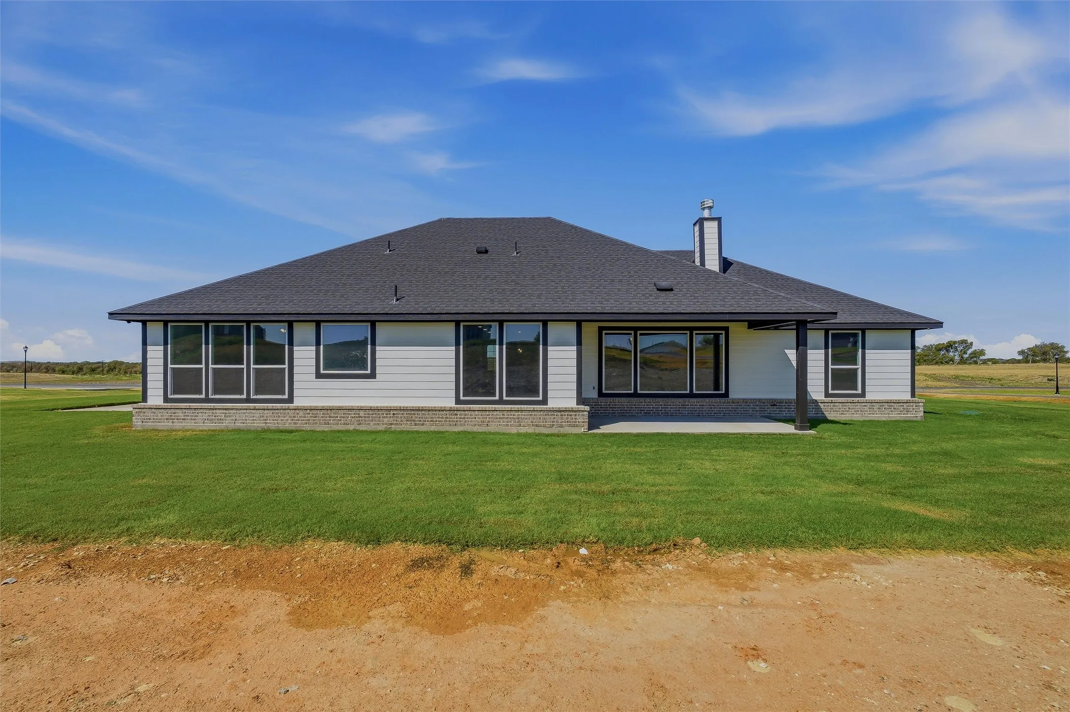 White siding exterior with a dark shingle roof and a covered patio