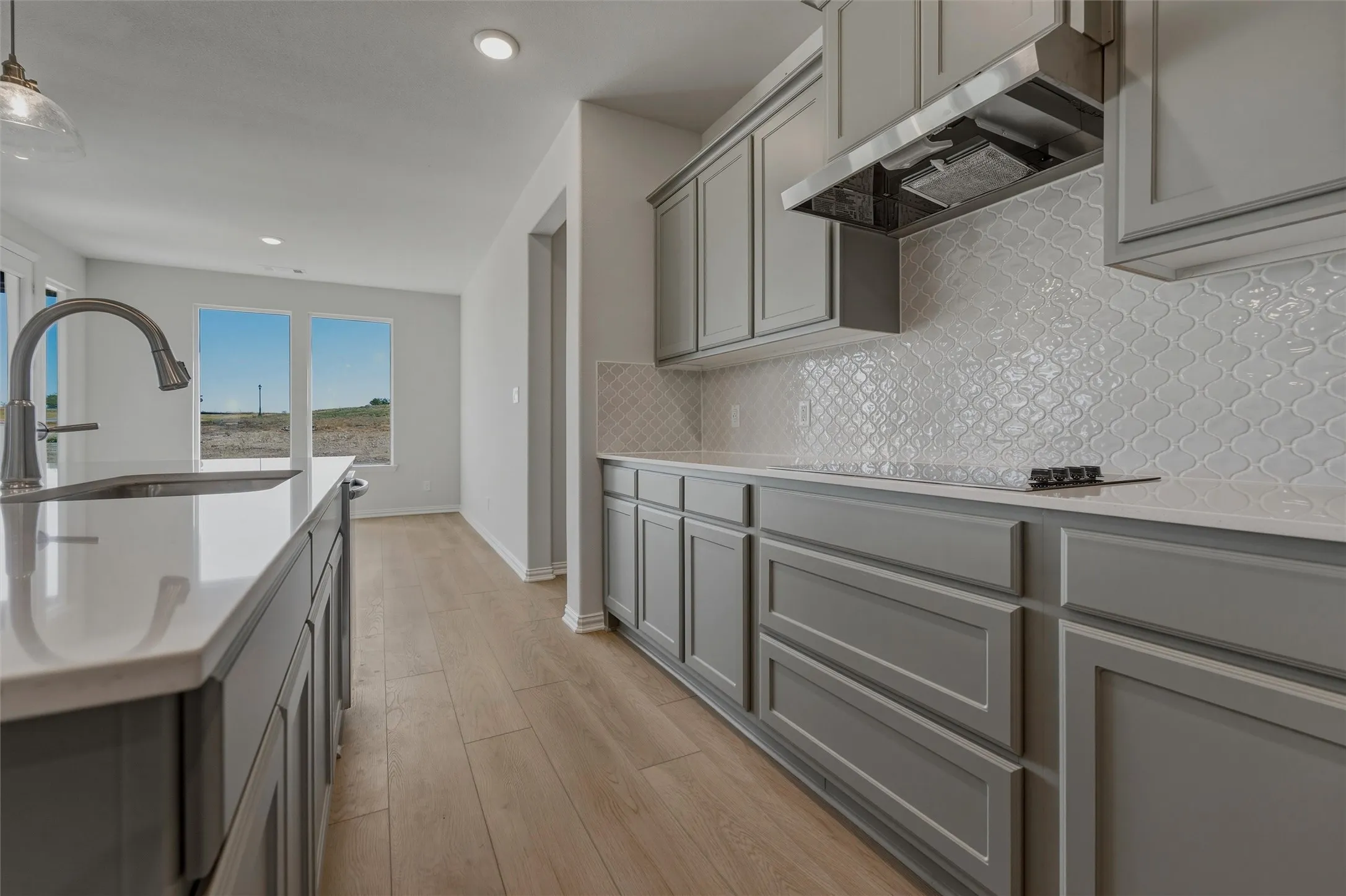 Kitchen featuring wood-finish flooring, recessed lighting, and a kitchen island with an undermount sink and gooseneck faucet
