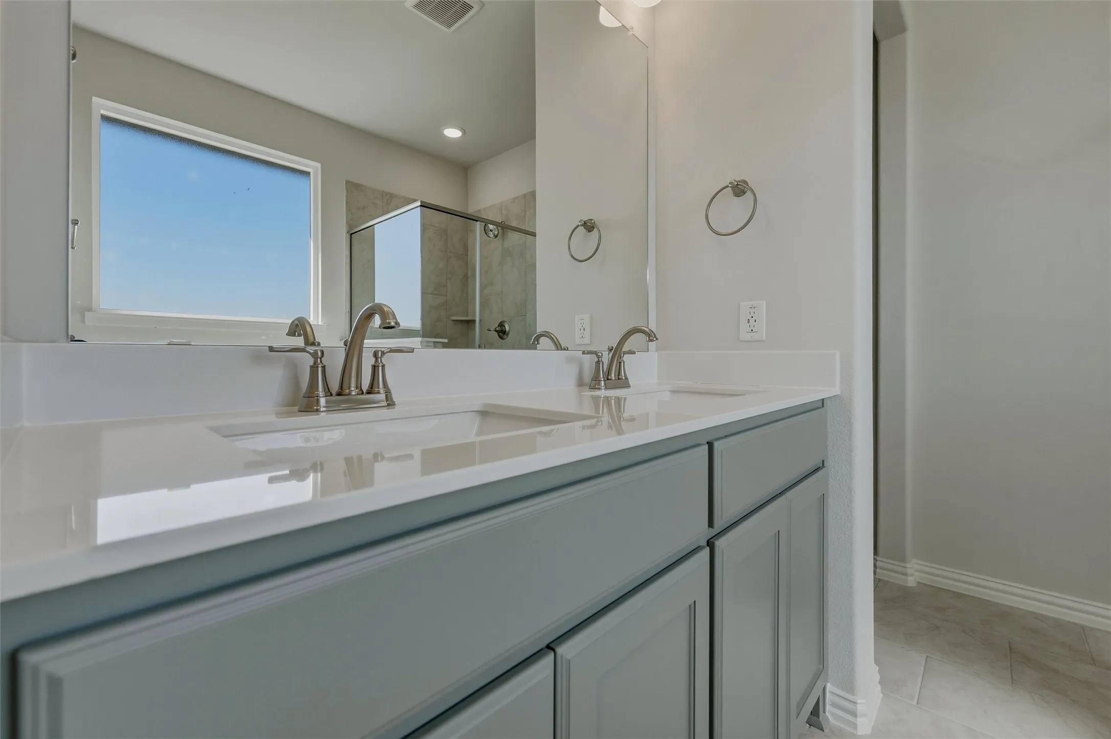 Dual vanity with undermount sinks, light-toned countertops, and brushed nickel fixtures
