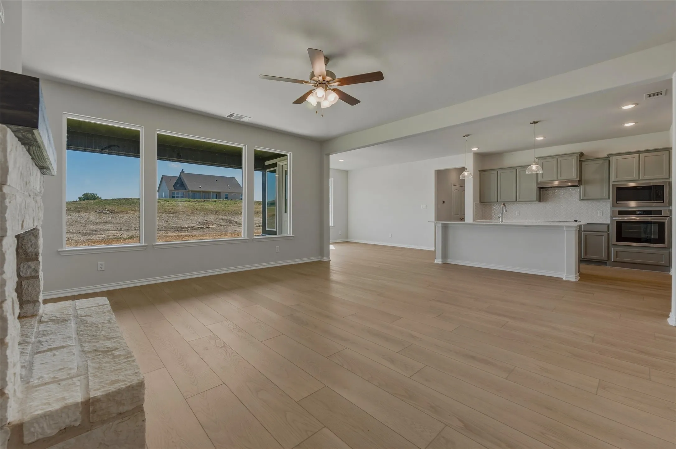 Spacious interior with wood-finish flooring, a stone-clad fireplace, and multiple windows