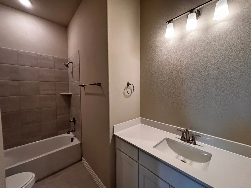 White vanity with an integrated sink, brushed nickel faucet, and a wall-mounted light fixture