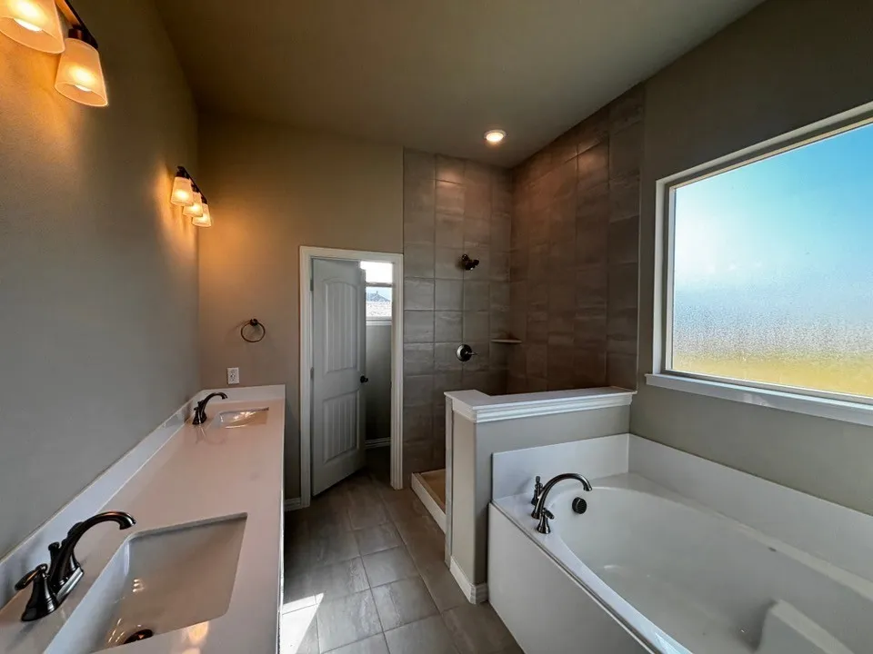 Dual vanity with integrated sinks, a built-in soaking tub, and a shower with tiled walls