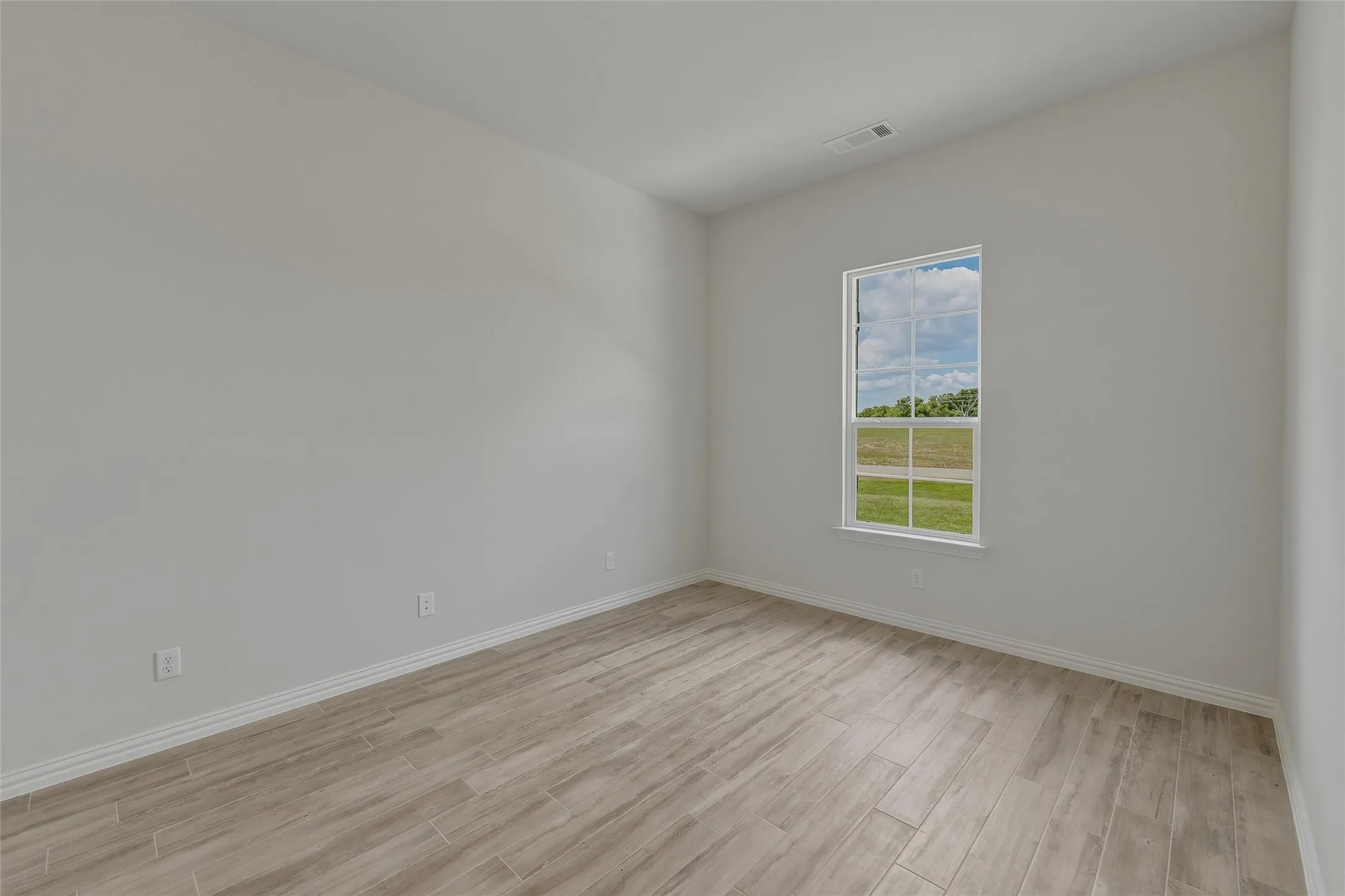 Light-filled interior featuring neutral wall tones, wood-finish flooring, and a multi-pane window