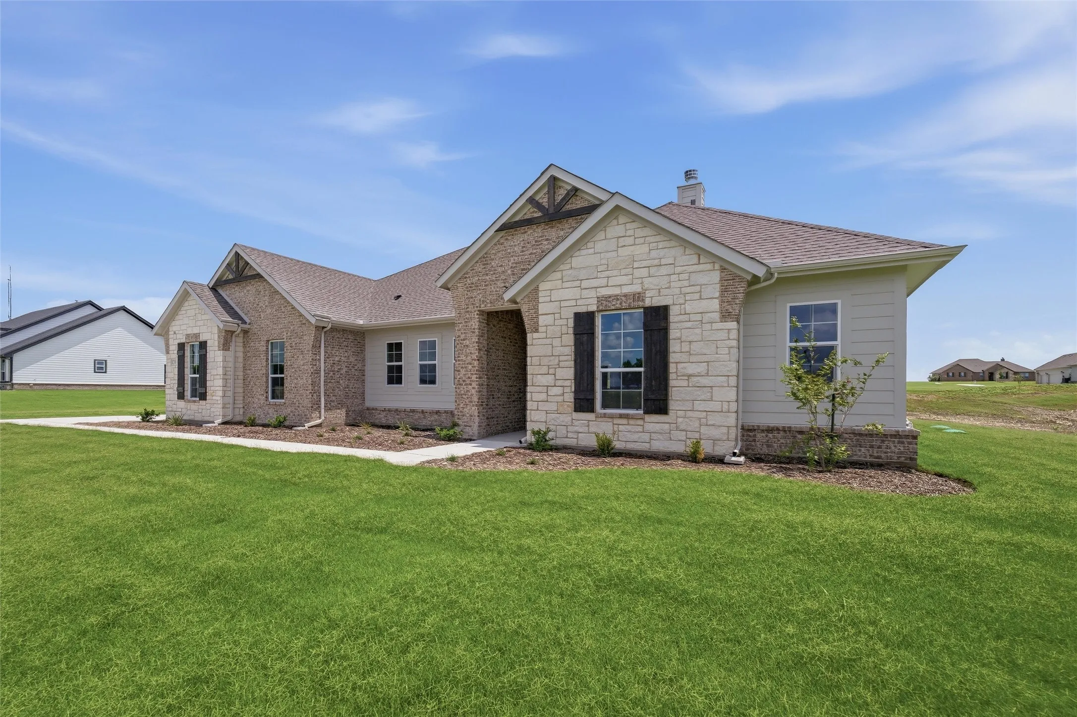 Exterior featuring brick and stone cladding, gabled rooflines, decorative timber accents, and dark window shutters