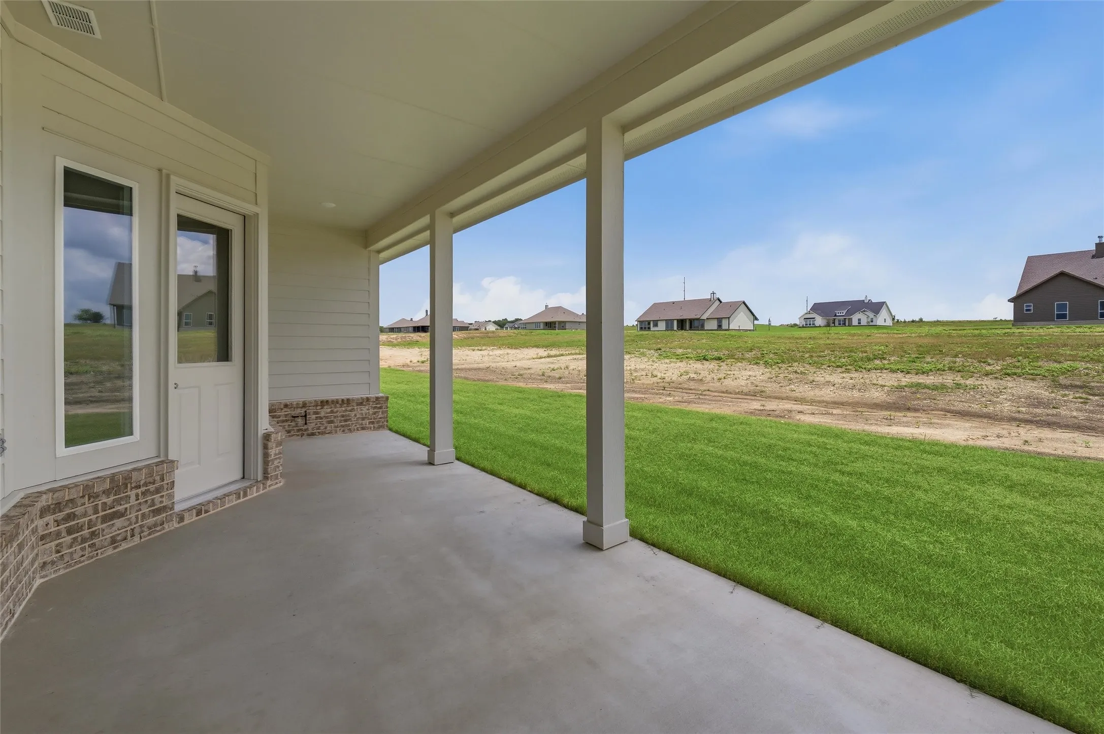 Covered concrete patio with siding and brick accent wall