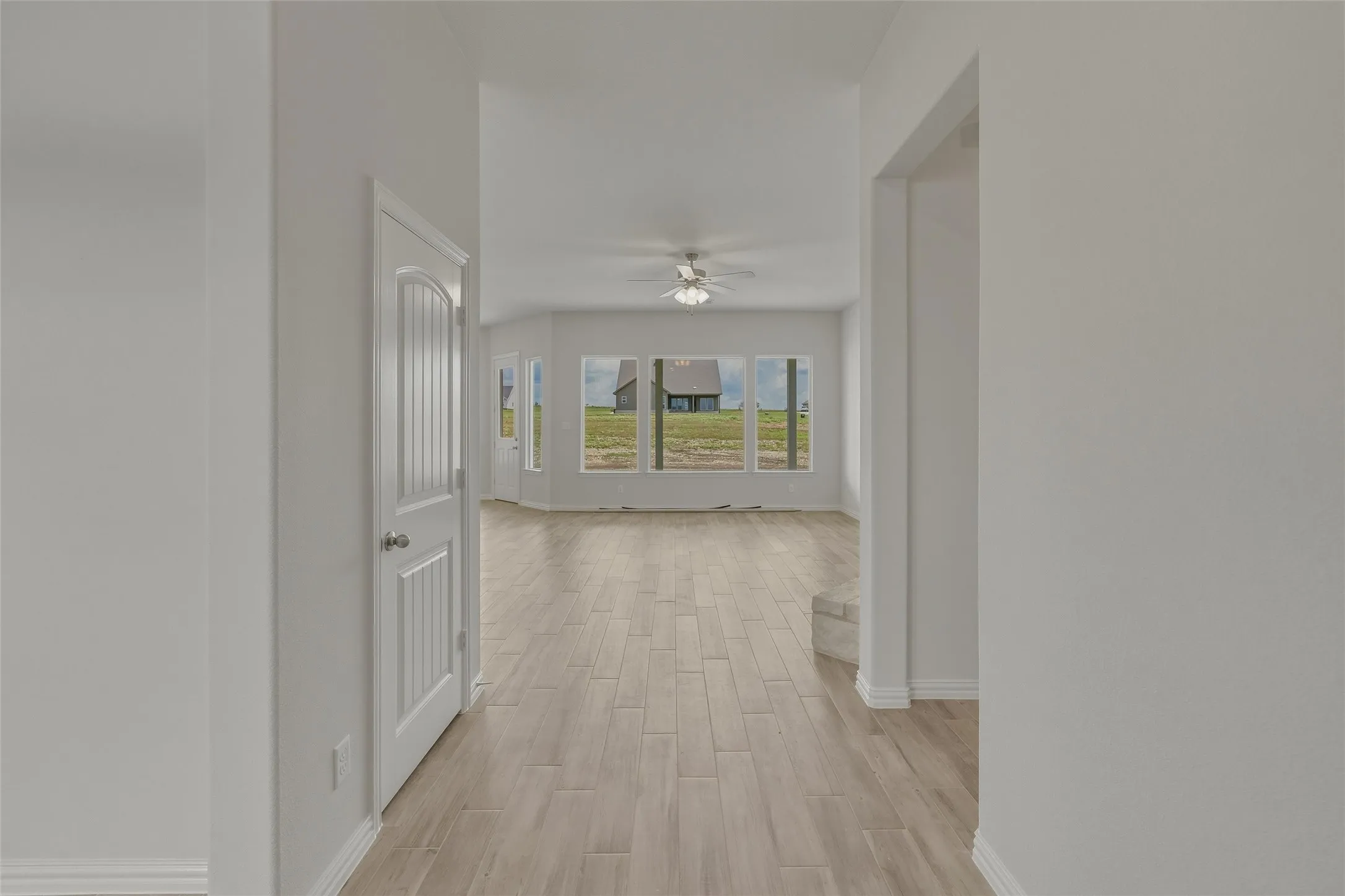 Wood-finish flooring throughout, bright white walls, and a recessed ceiling fan
