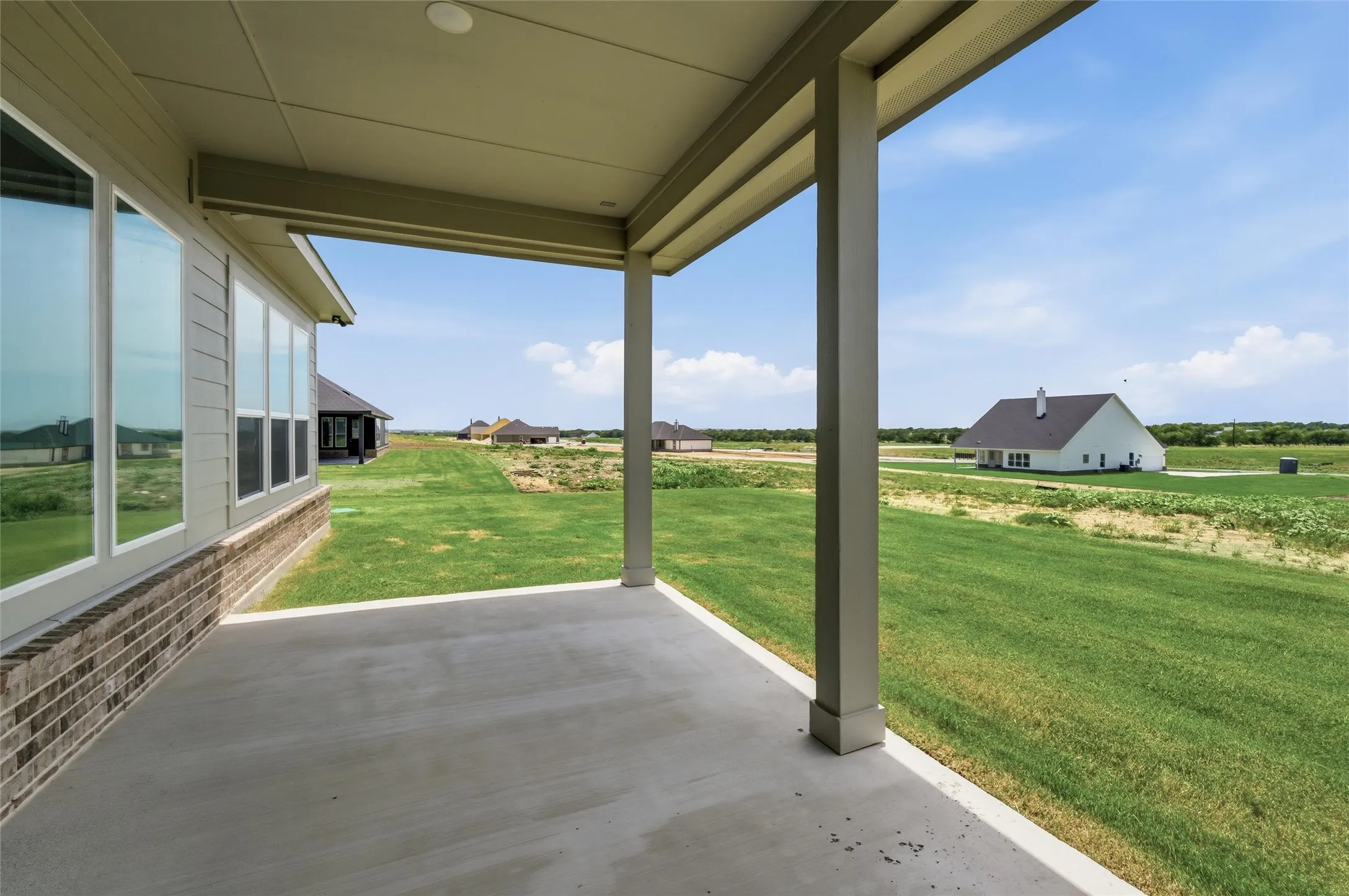 Covered patio with a concrete surface, supported by sturdy columns