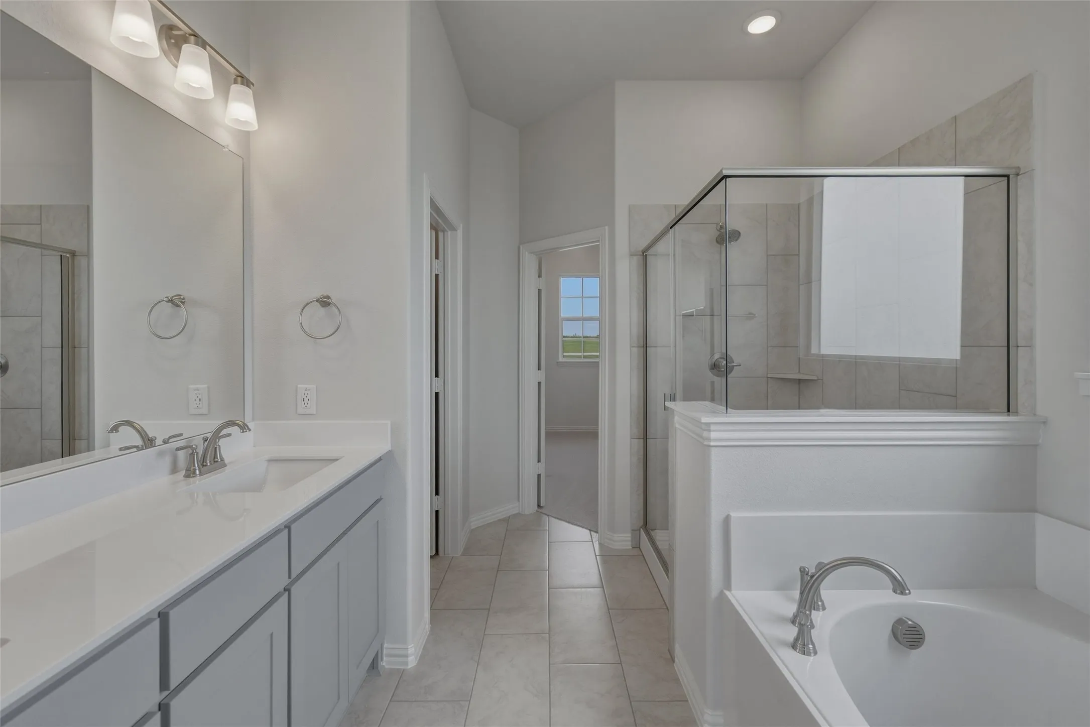 Double vanity with integrated sinks, brushed nickel fixtures, a glass-enclosed shower, a built-in tub, and tile flooring