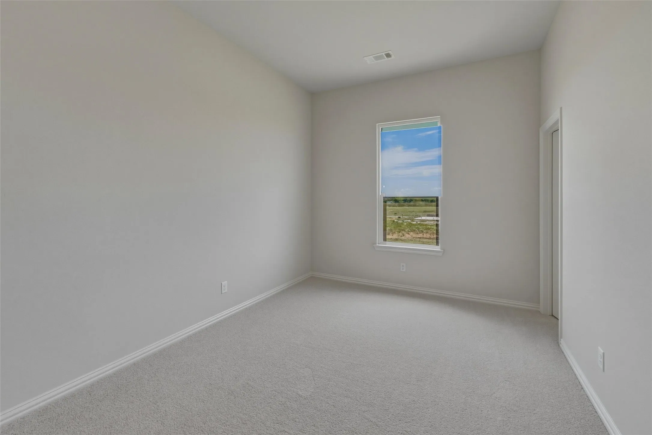 Neutral wall tones with a single window, light-toned carpet, and white trim