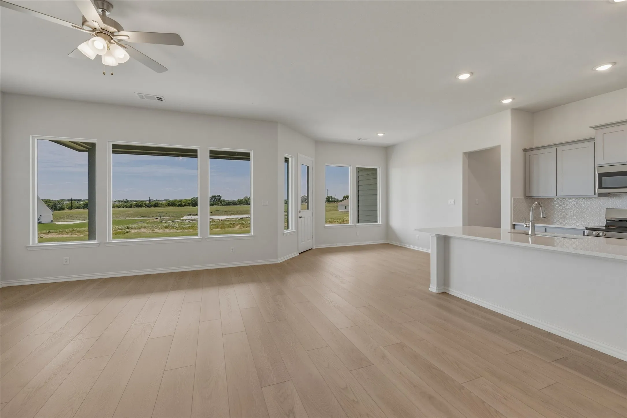 Wood-finish flooring throughout, recessed lighting, and a ceiling fan with integrated light