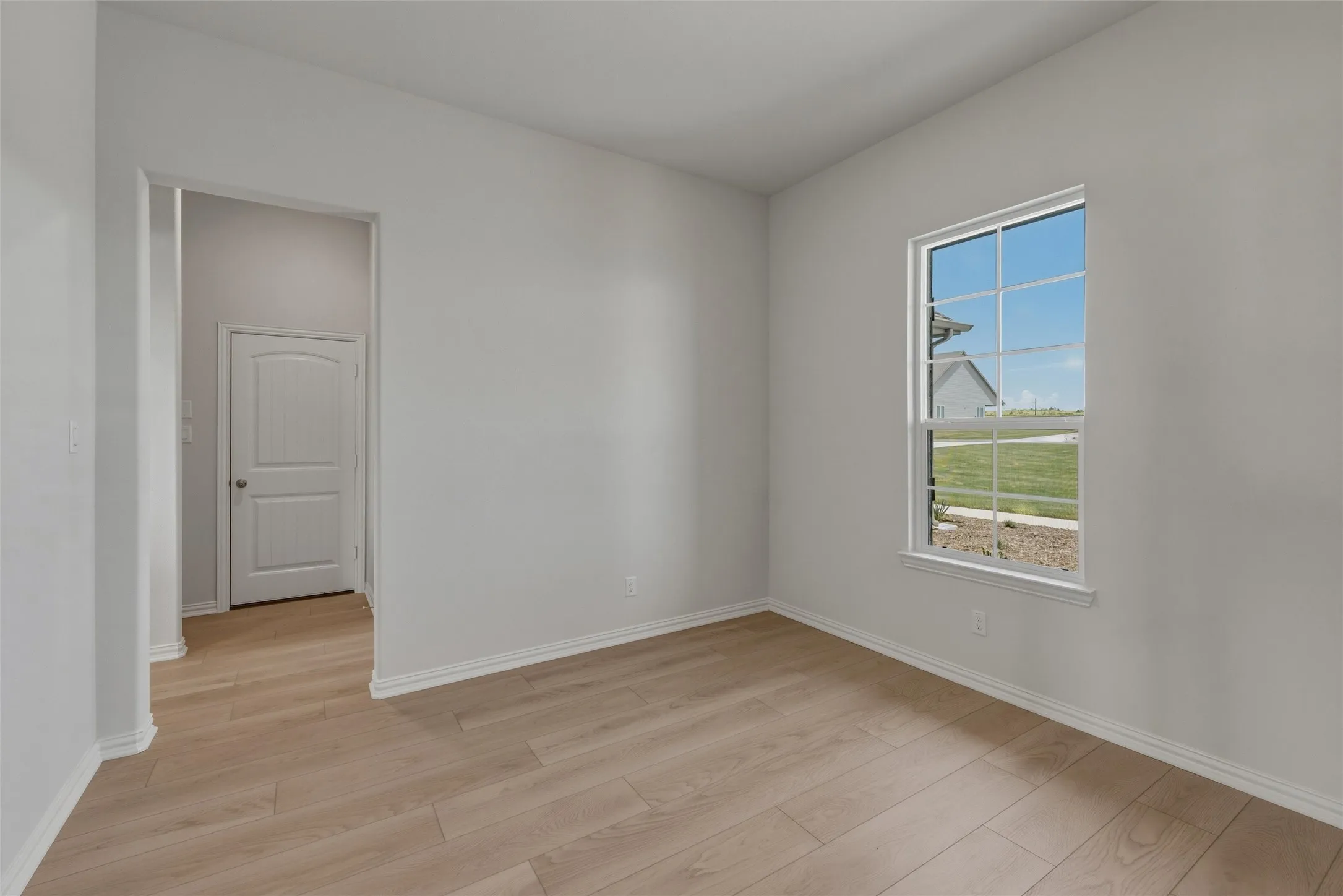 Light wood-finish flooring, white walls, and a multi-pane window