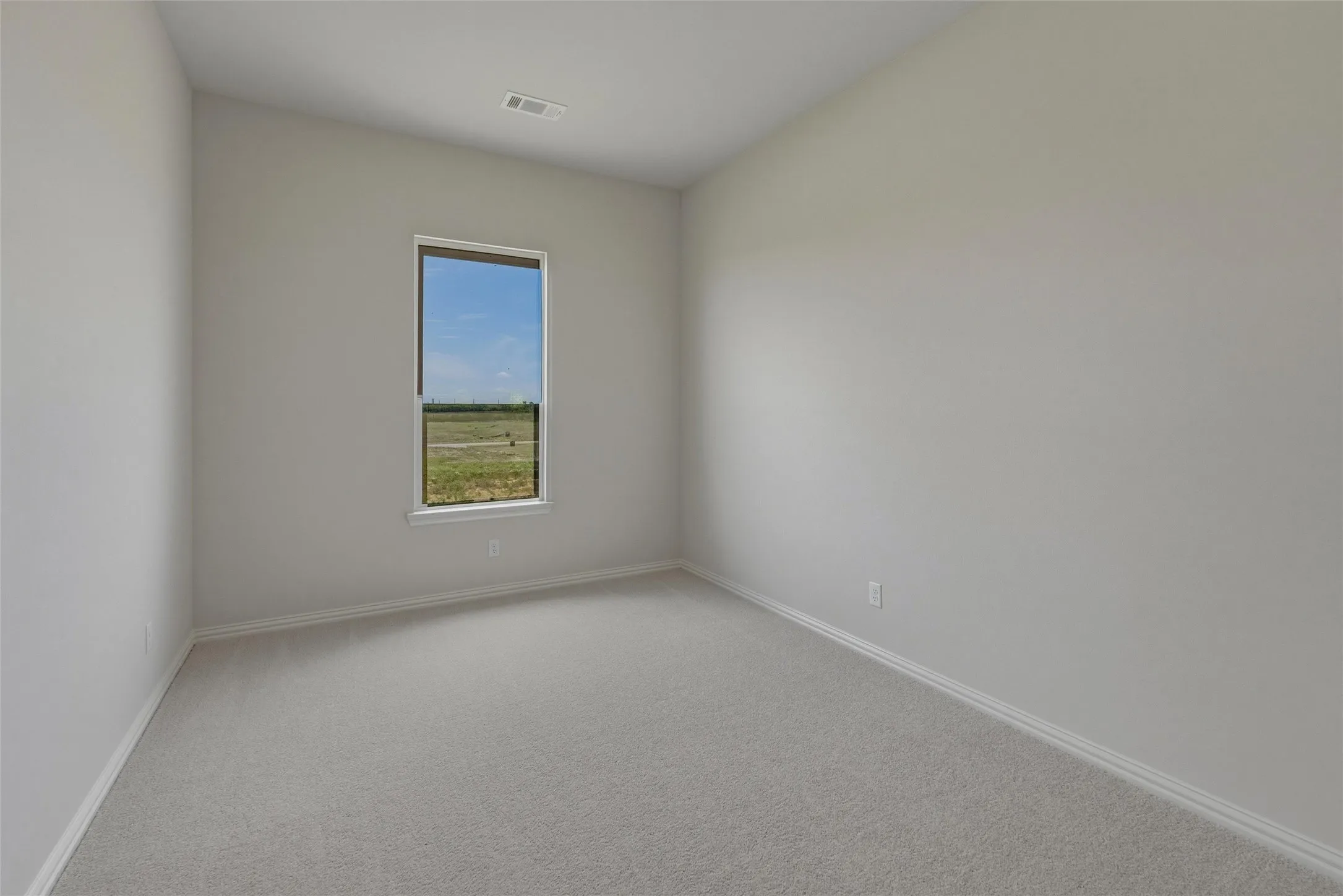 Neutral wall paint, single window, gray carpet flooring, white trim