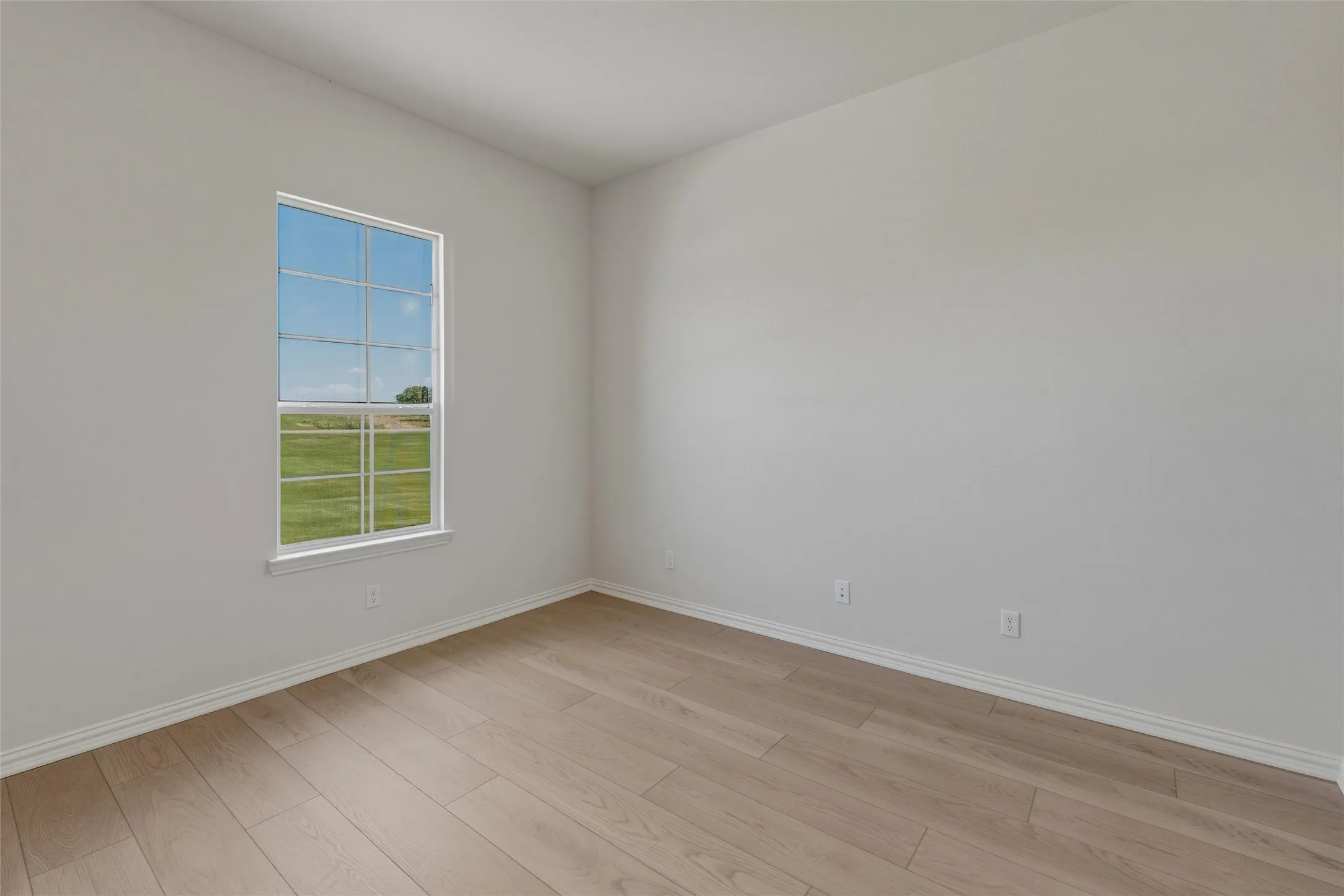 Light wood-finish flooring, white walls, and a large window with white trim