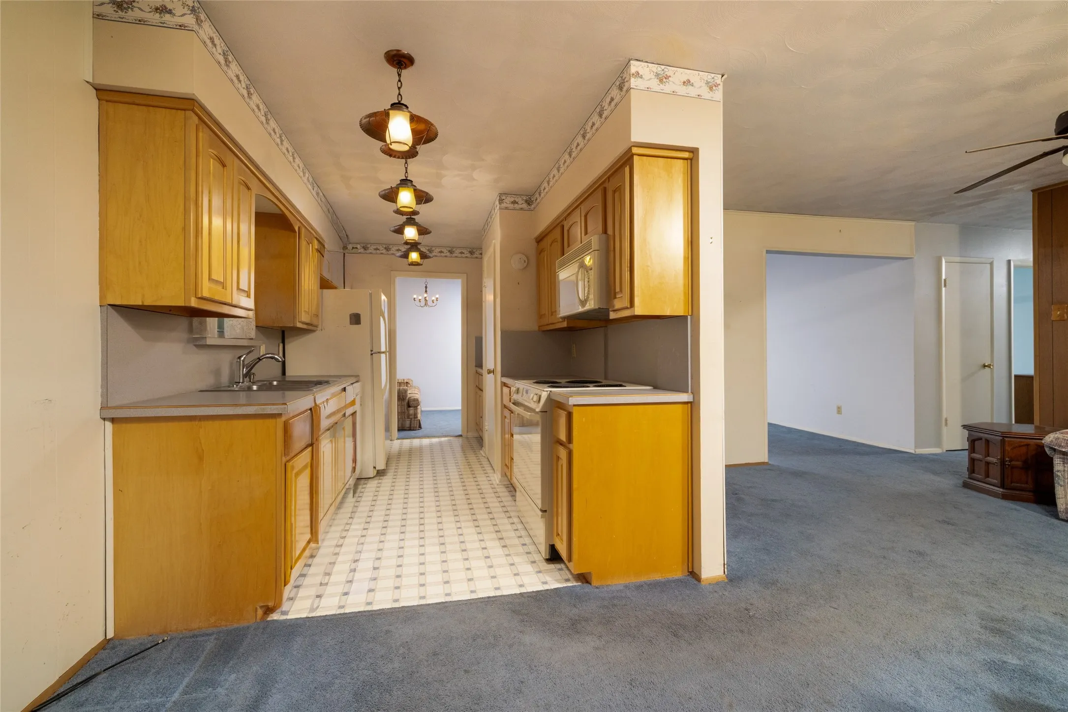 Wood-finish cabinetry with laminate countertops, a stainless steel sink, and a tiled backsplash