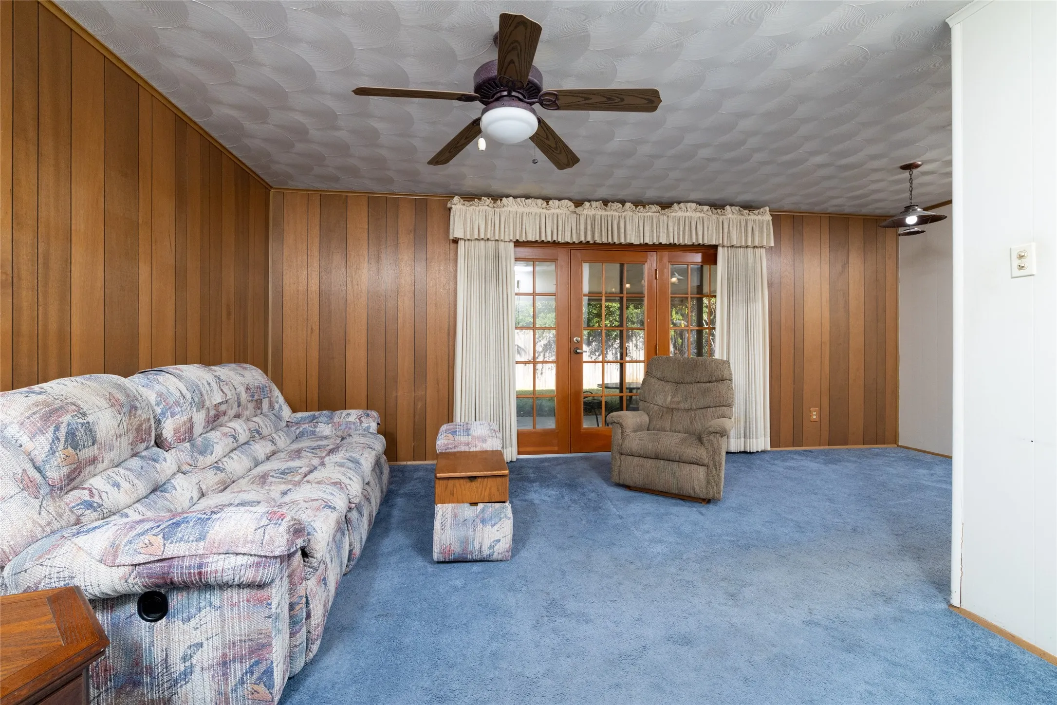 Spacious wood-paneled room with ceiling fan and recessed lighting