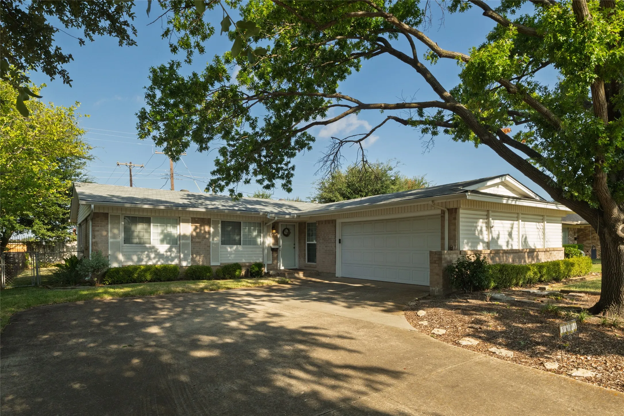 Ranch-style residence featuring a prominent two-car garage, brick and siding exterior, and a concrete driveway