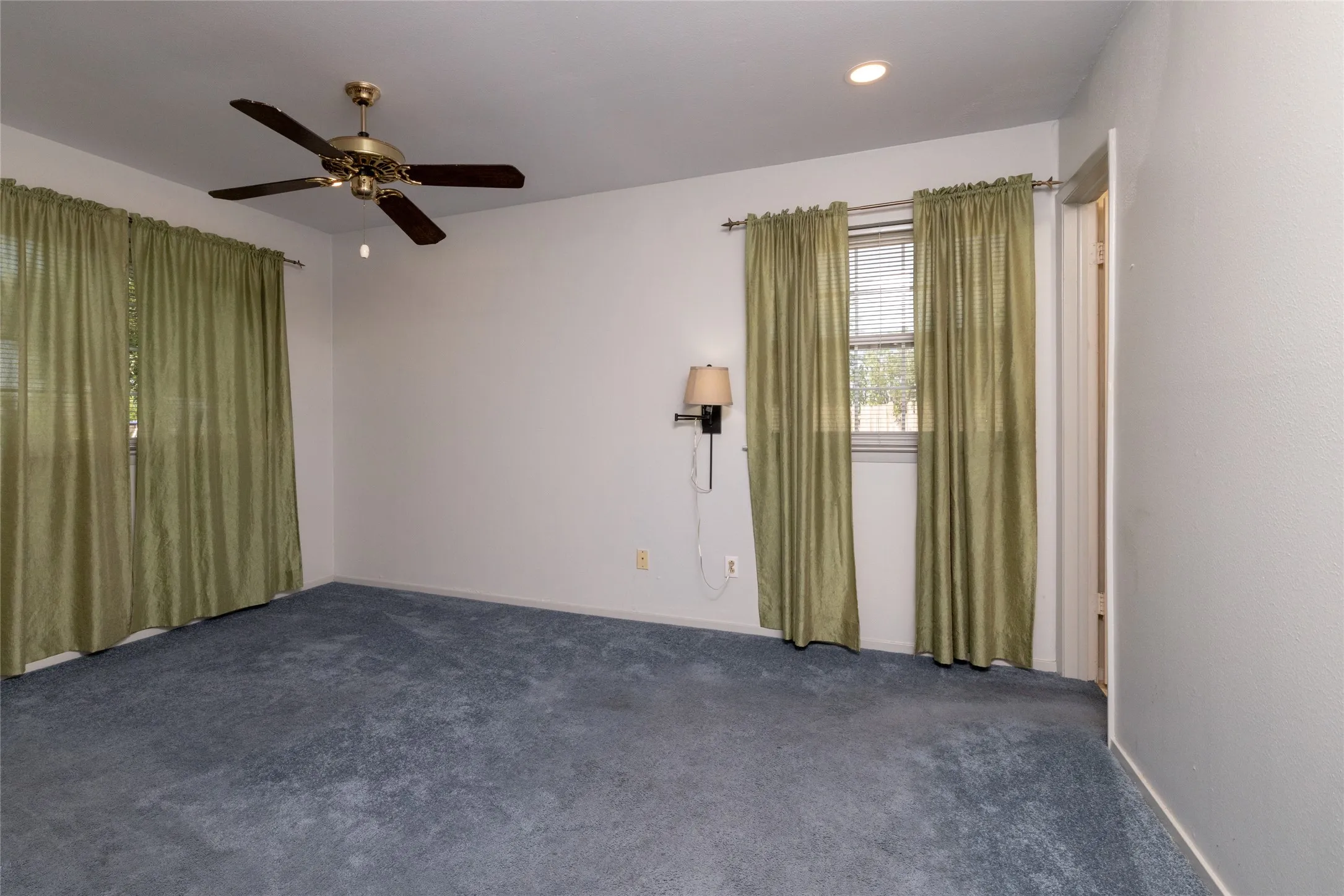 Carpeted room with a ceiling fan, recessed lighting, and a window with blinds