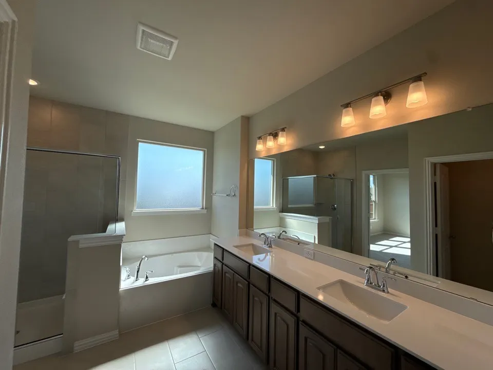 Double vanity with integrated sinks, full-width mirror, and overhead lighting
