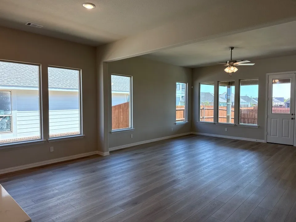 Open-concept living area featuring wood-finish flooring, recessed lighting, a ceiling fan, and multiple windows