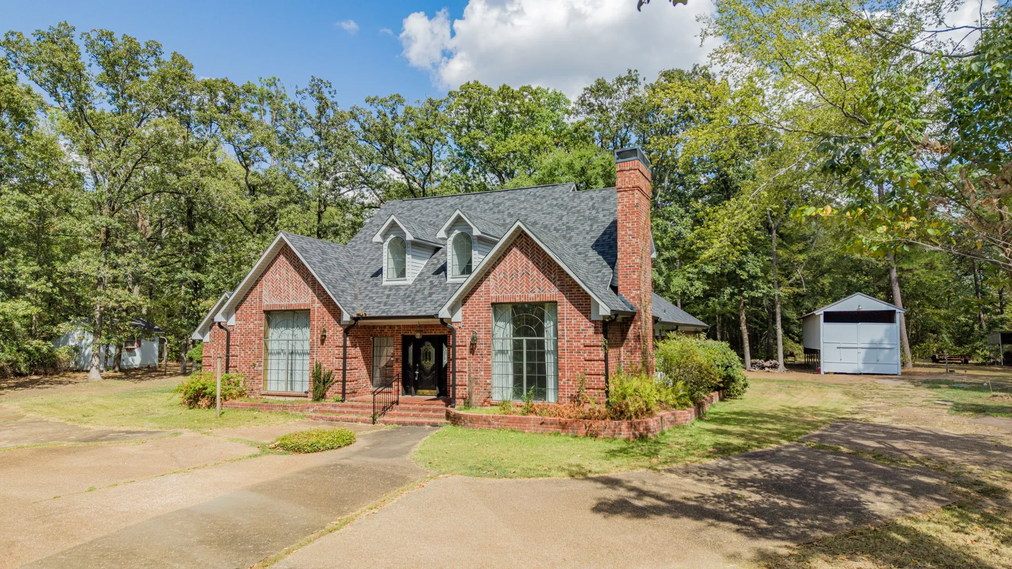 Brick exterior with a dark shingle roof, featuring multiple dormer windows