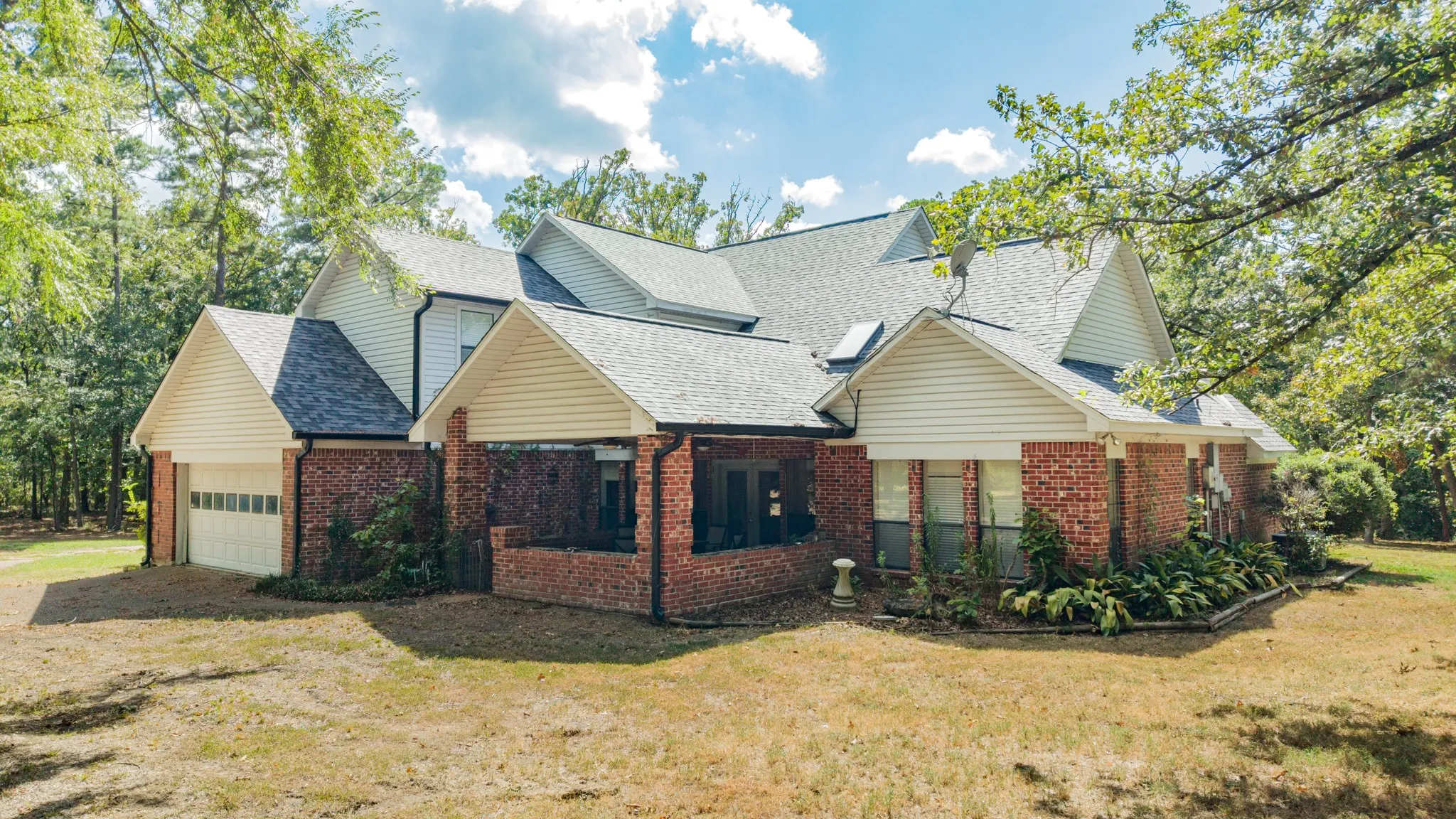 Brick and siding exterior with multiple gables, an attached garage, and established landscaping