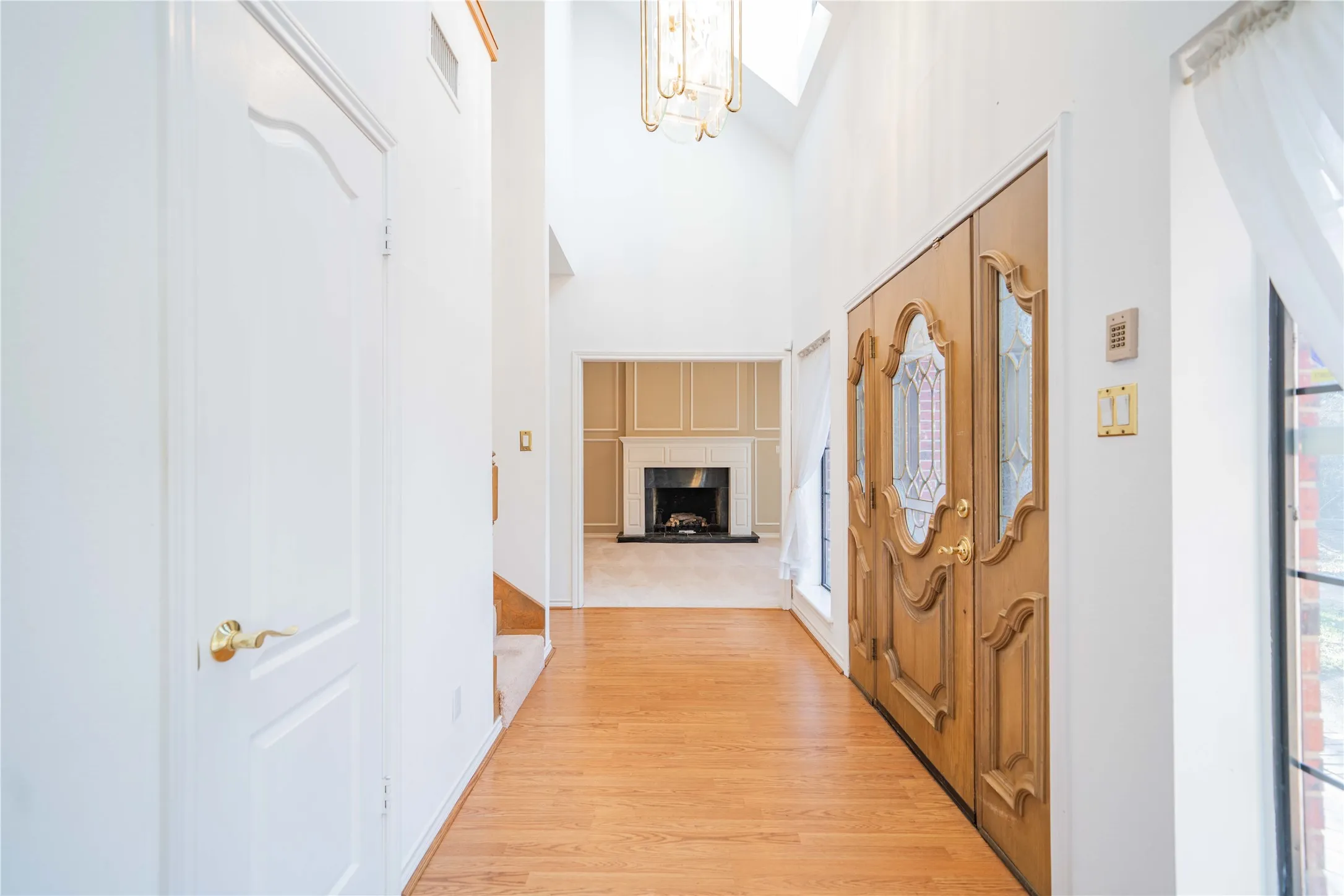 Two-story foyer featuring wood-finish flooring, a decorative chandelier, and an ornate double-door entry with leaded glass panels