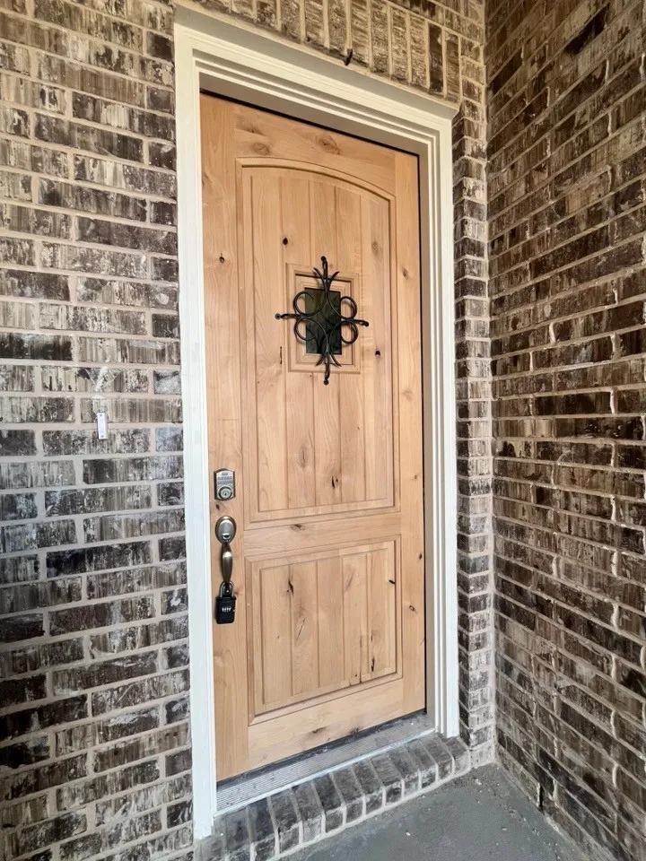Natural wood-tone entry door with decorative ironwork