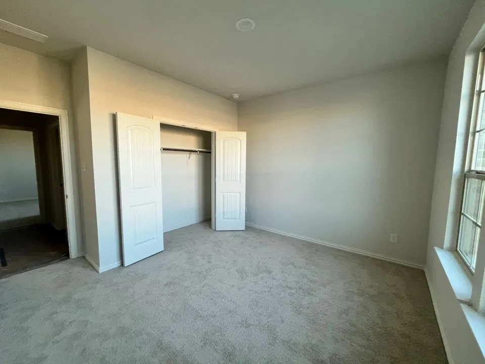 Neutral wall paint, light gray carpet flooring, recessed ceiling lighting, and a window with white trim