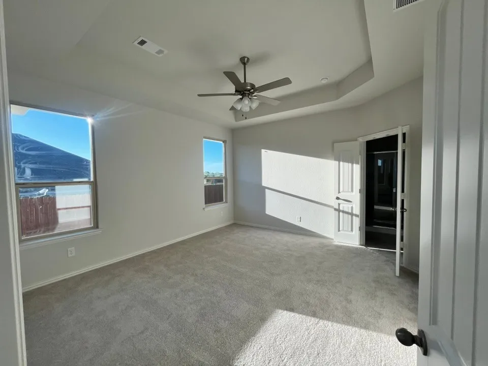 Recessed tray ceiling, neutral wall tones, two pane windows, ceiling fan, and carpeted flooring
