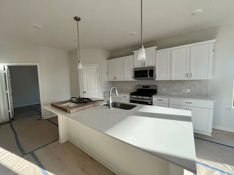 Kitchen featuring white cabinetry, stainless steel appliances, a center island with sink, pendant lighting, and recessed ceiling lights
