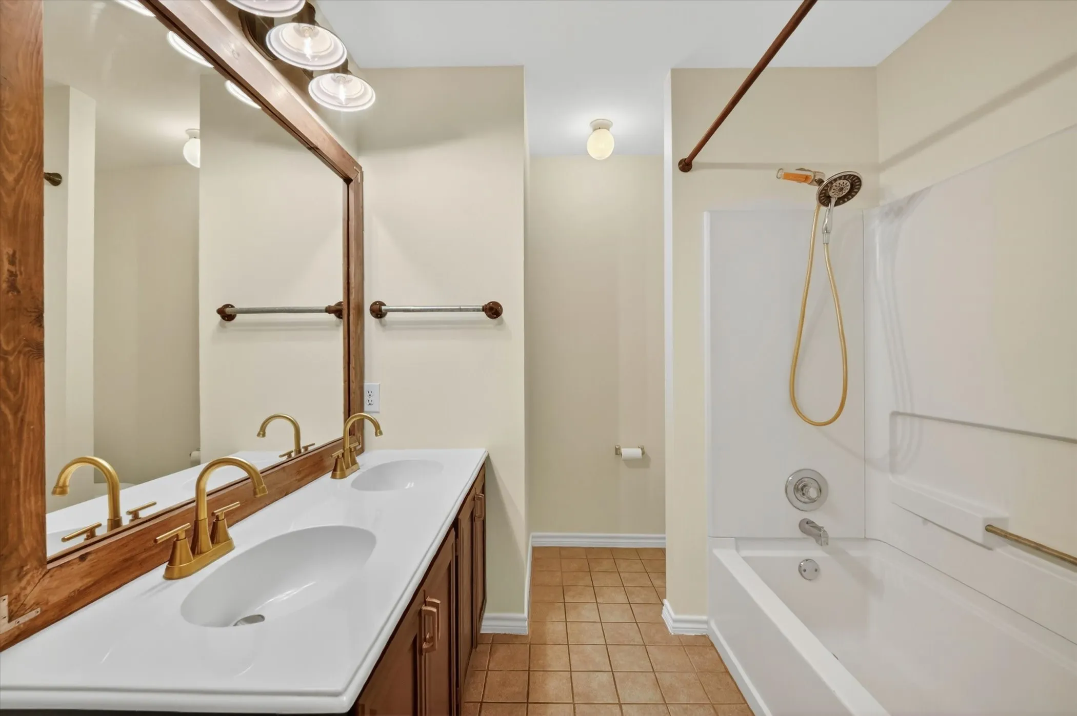 Dual vanity with integrated sinks, brushed gold faucets, and a wood-framed mirror
