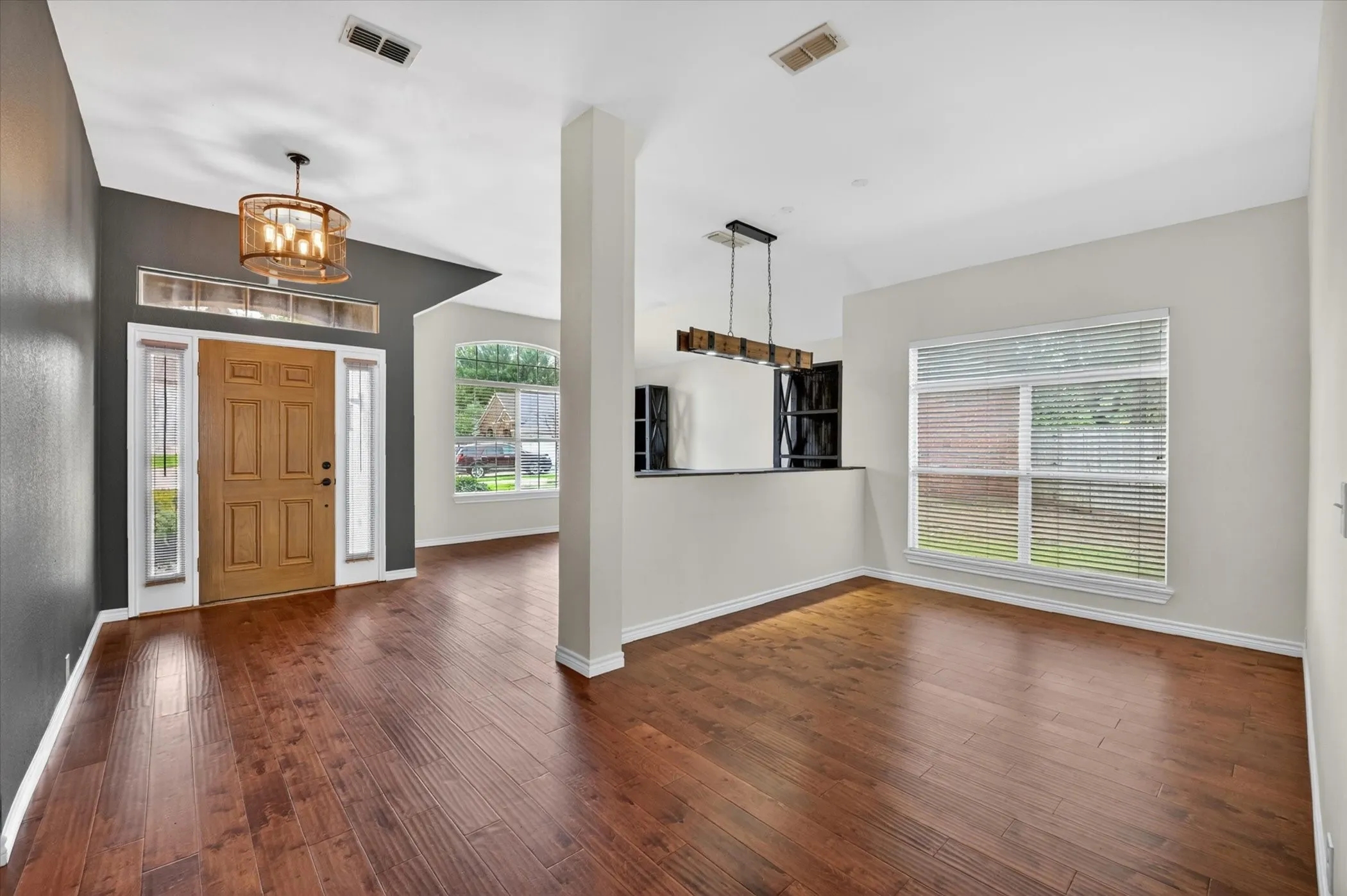 Wood-finish flooring throughout, with a decorative entry chandelier, and a prominent front door with sidelights and transom window