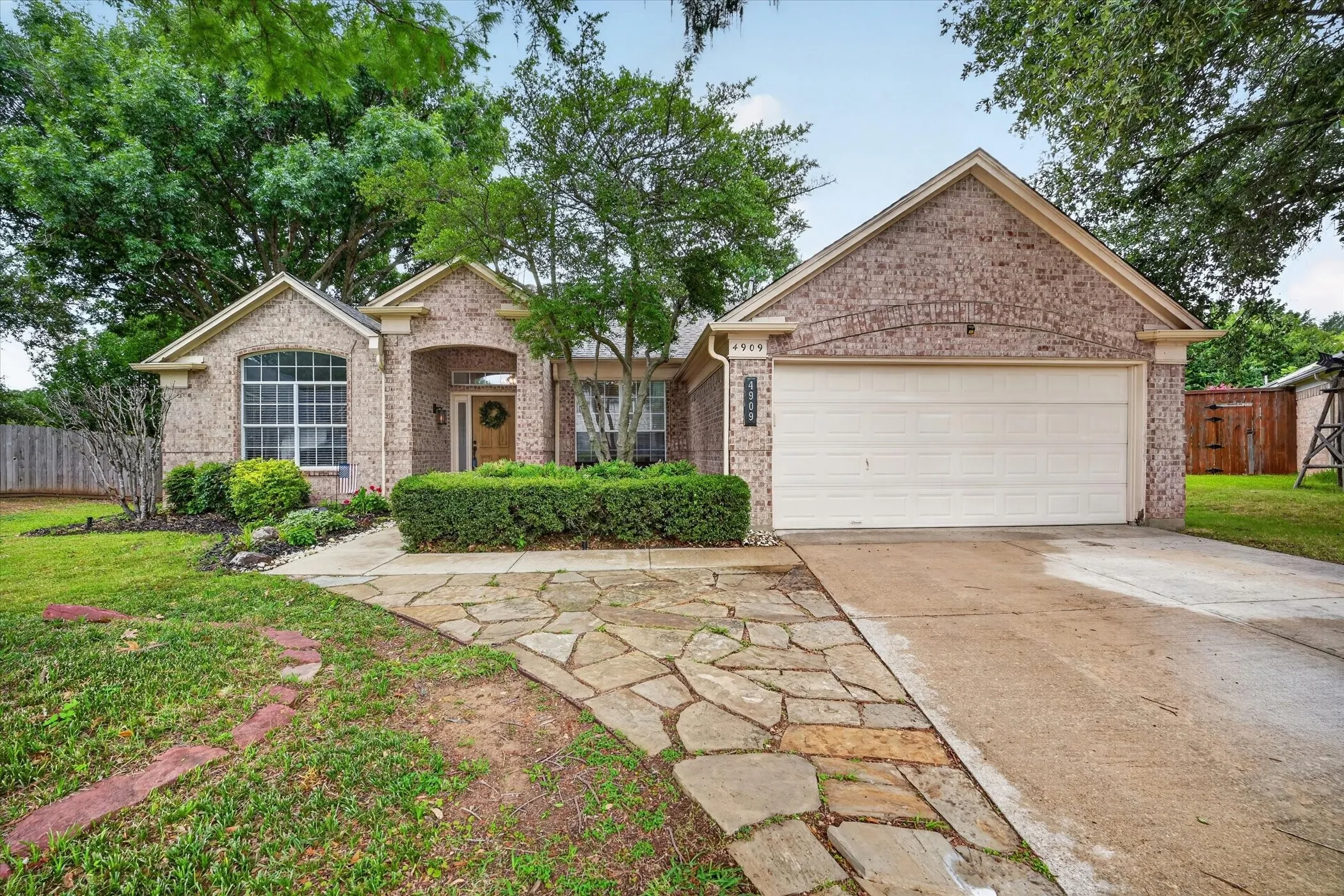 Brick exterior with arched entry, an integrated two-car garage, and a stone-paver walkway
