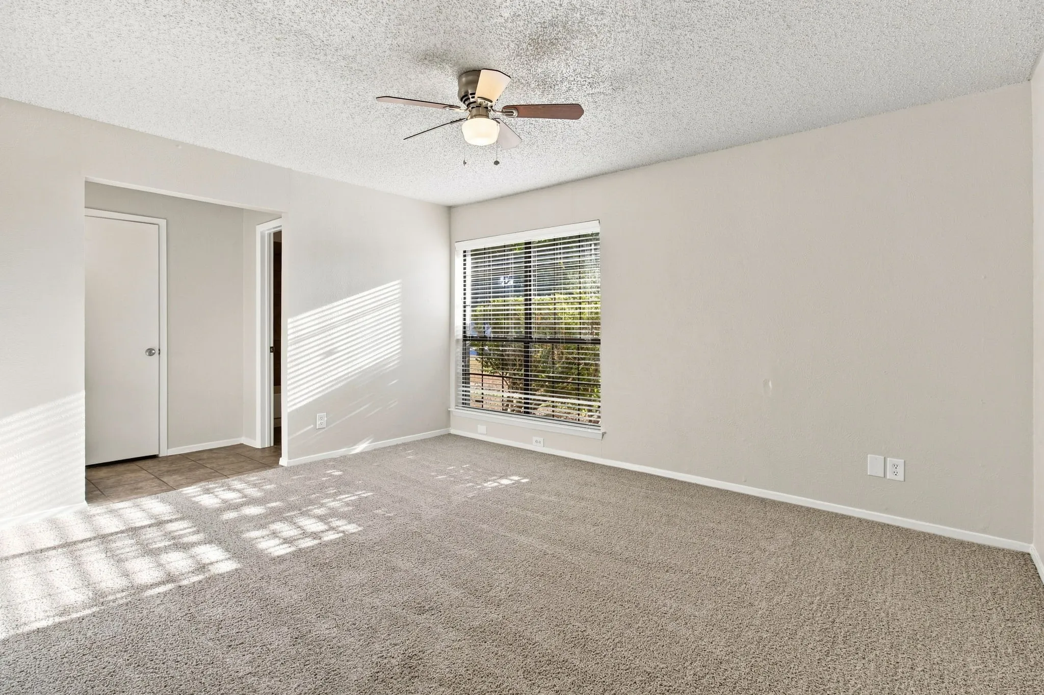 Room featuring neutral carpet, a ceiling fan with integrated lighting, window with blinds, and light-toned walls