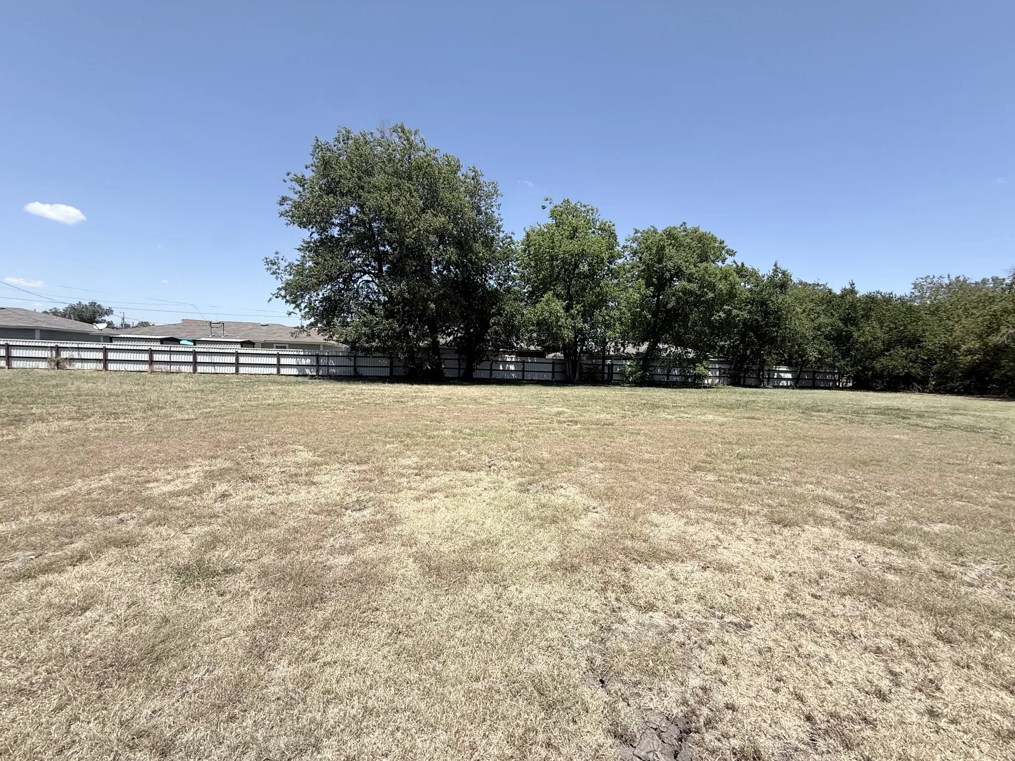 Expansive lot featuring a perimeter fence and mature trees