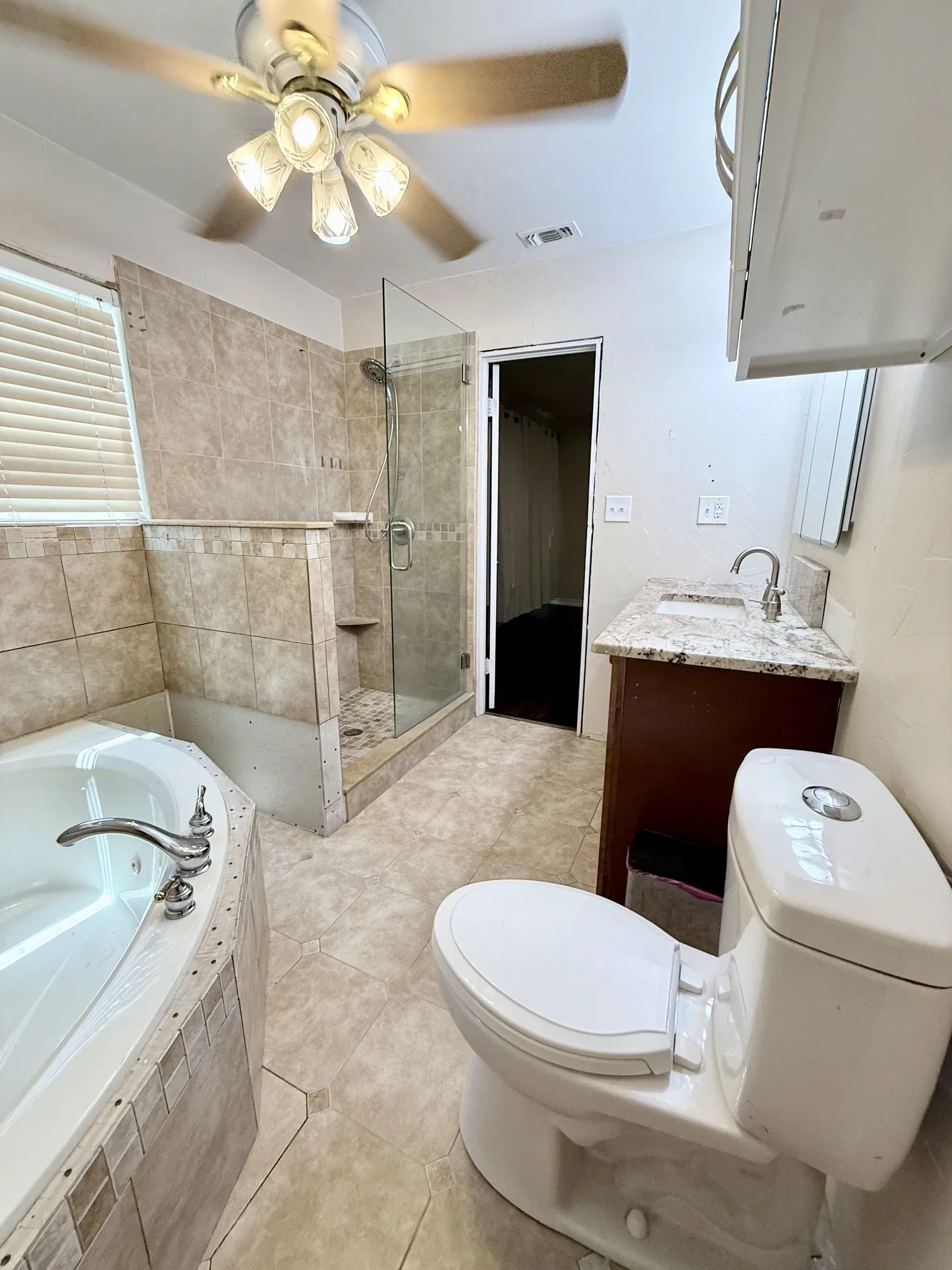 Tiled shower with glass enclosure, separate soaking tub, and a dual-sink vanity with a light-colored countertop